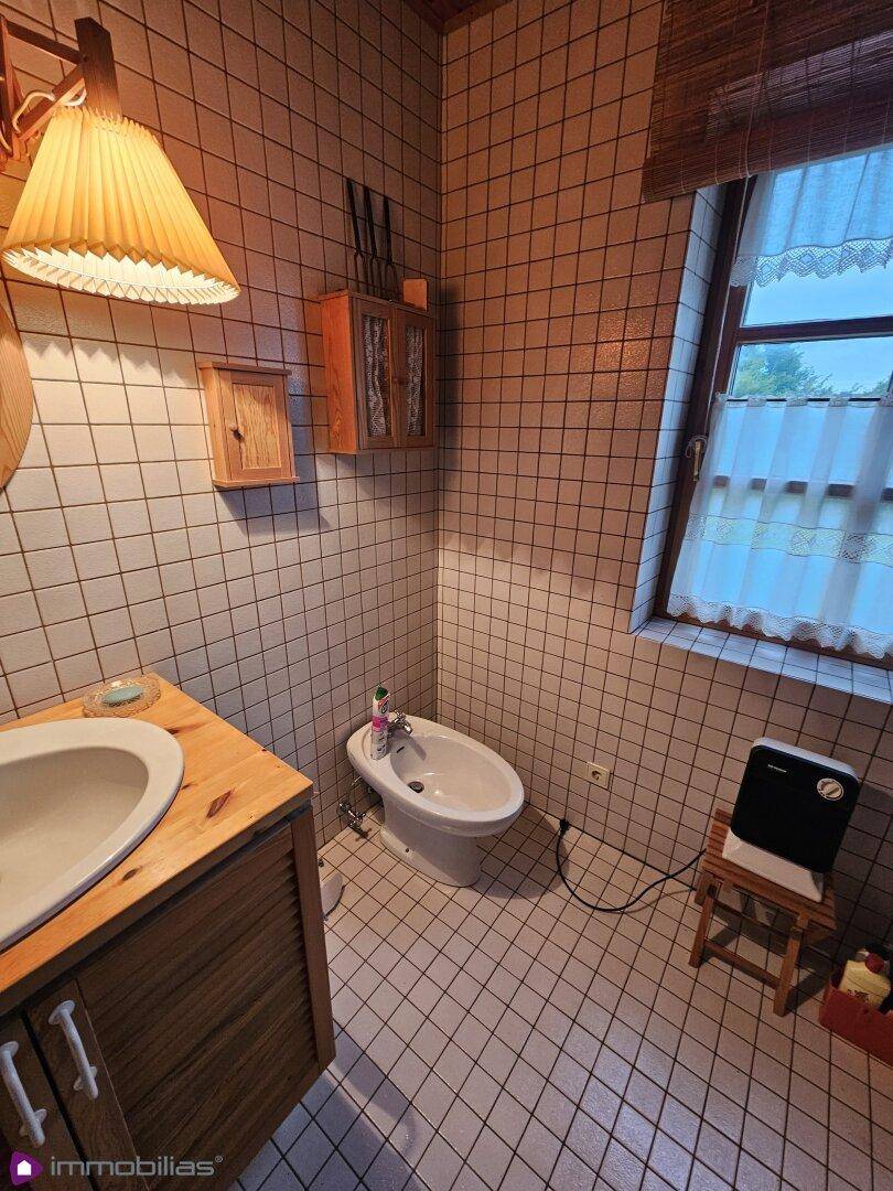 Badezimmer mit Bidet, Waschbecken und Fenster, hell und sauber gefliest.