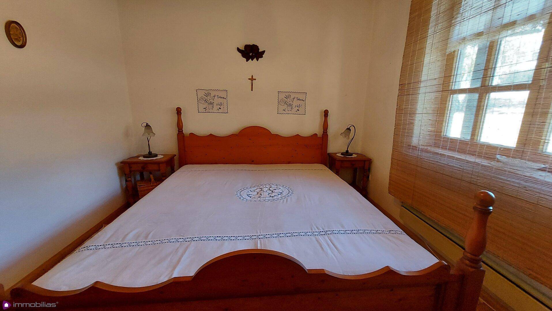Helles Schlafzimmer mit traditionellem Holzdoppelbett und Nachttischen, sehr einladend.
