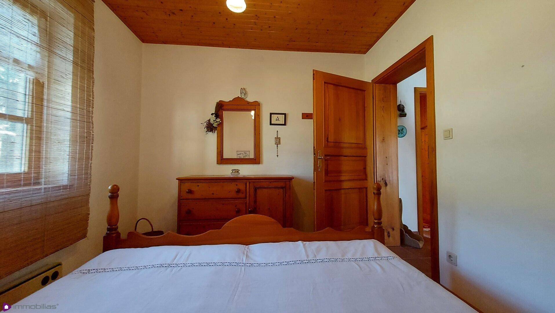 Gemütliches Schlafzimmer mit Doppelbett, Holzmöbeln und Holzbalkendecke.