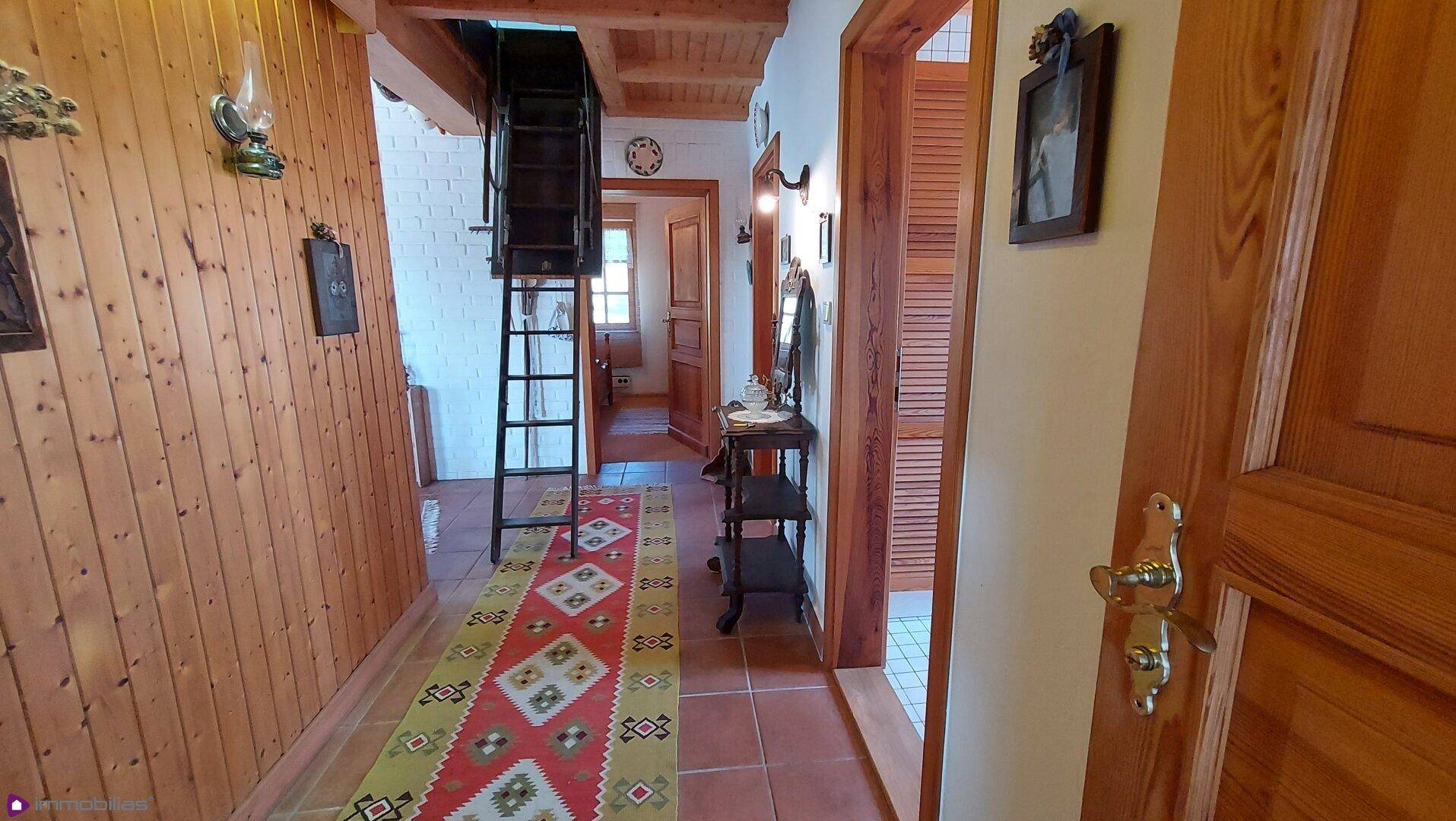 Rustikaler Flur mit Holzvertäfelung, Fliesenboden und Treppe zum oberen Stockwerk.