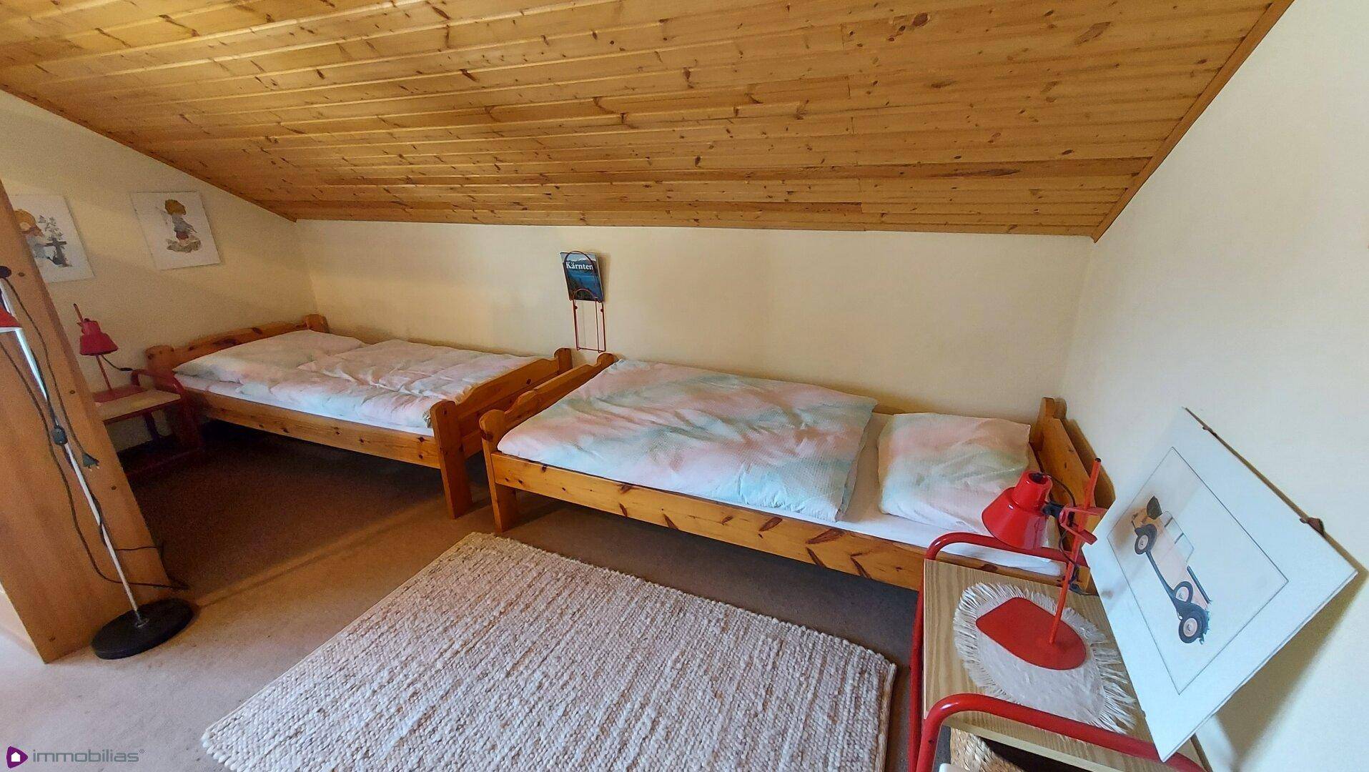 Gemütliches Schlafzimmer im Dachgeschoss mit zwei Einzelbetten und Holzdecke.