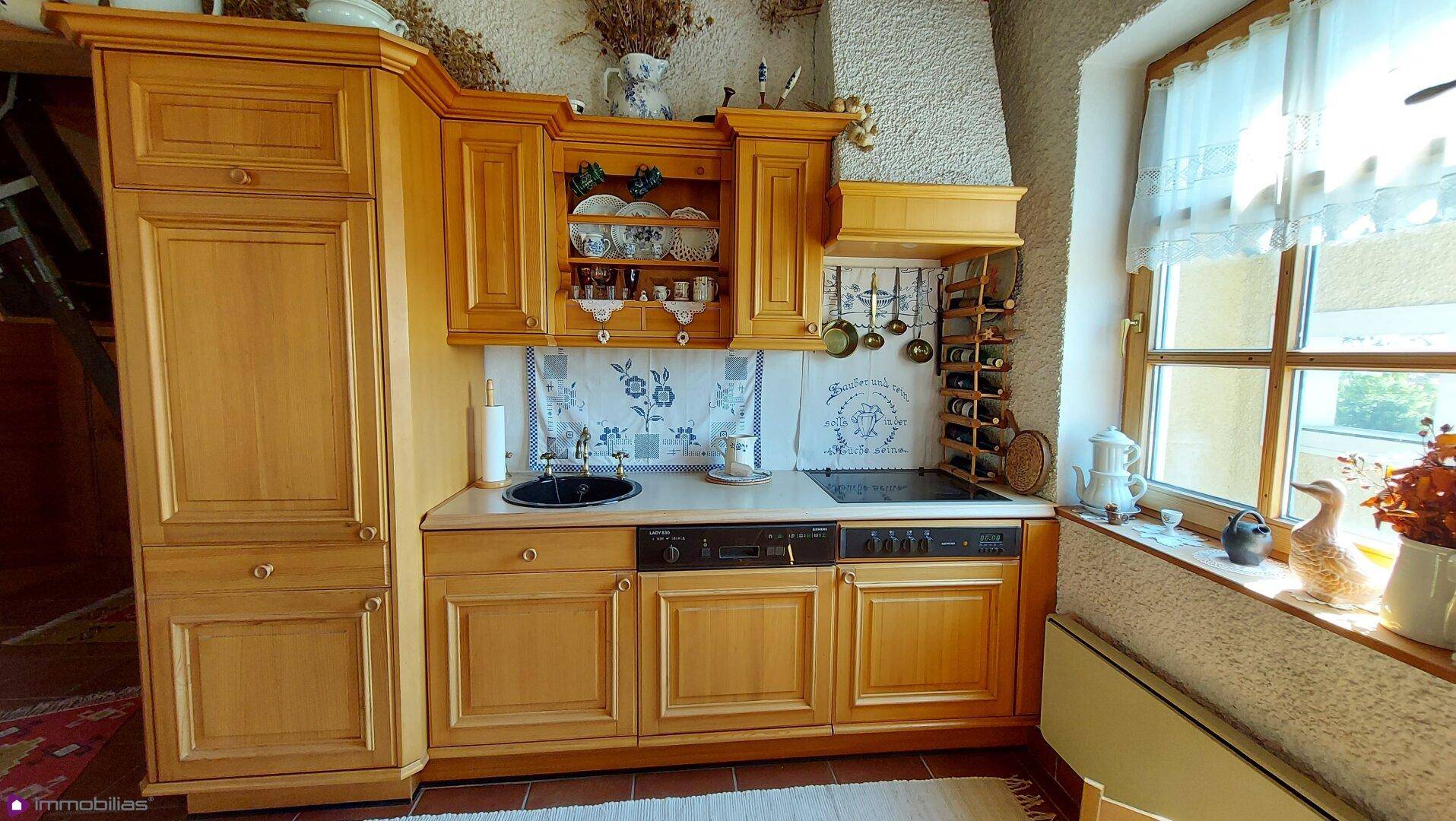 Voll ausgestattete Holzküche im Landhausstil mit integrierten Geräten und Fenster.