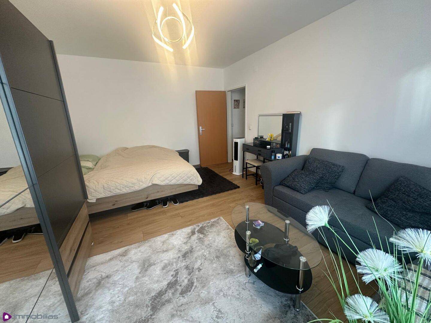 Kombinierter Wohn- und Schlafbereich mit Bett, Sofa und Schminktisch.