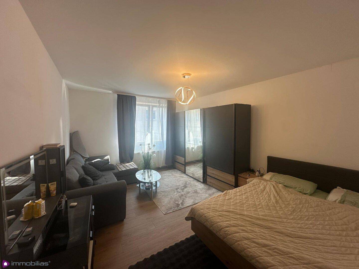Heller Schlafbereich mit Doppelbett, Sofa und großem Spiegelschrank.