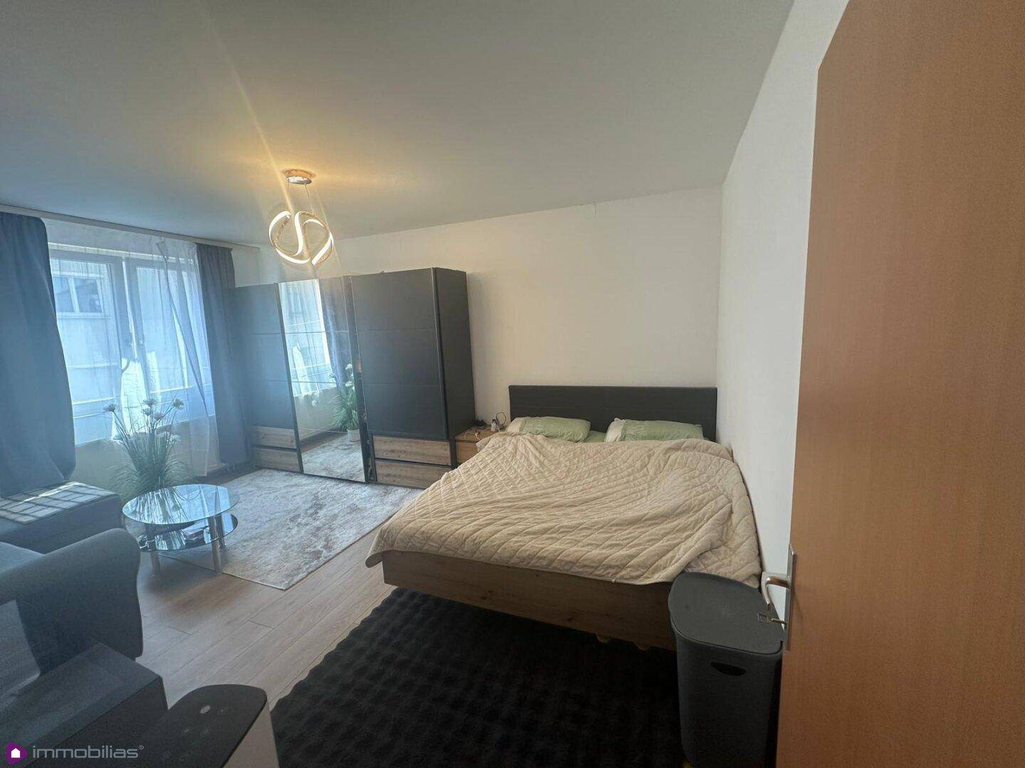 Schlafzimmer mit Doppelbett, Sofa und großem Kleiderschrank, hell und funktional.