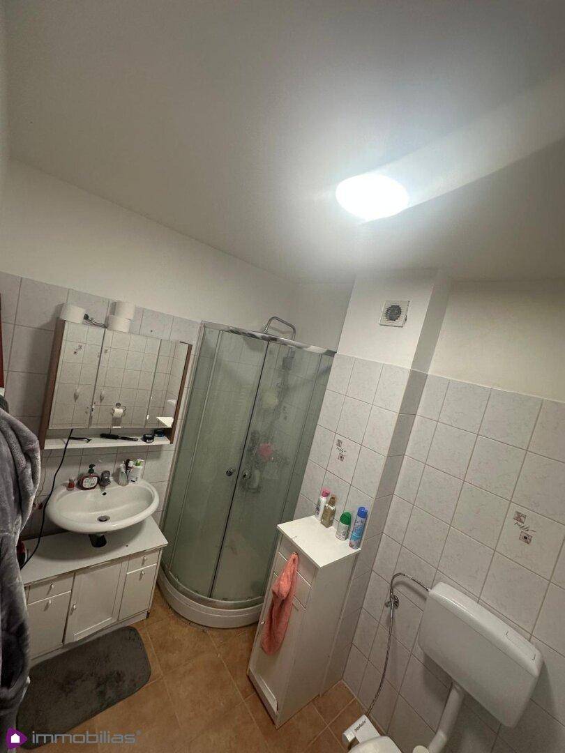 Funktionales Badezimmer mit Duschkabine, Waschbecken und Spiegelschrank.