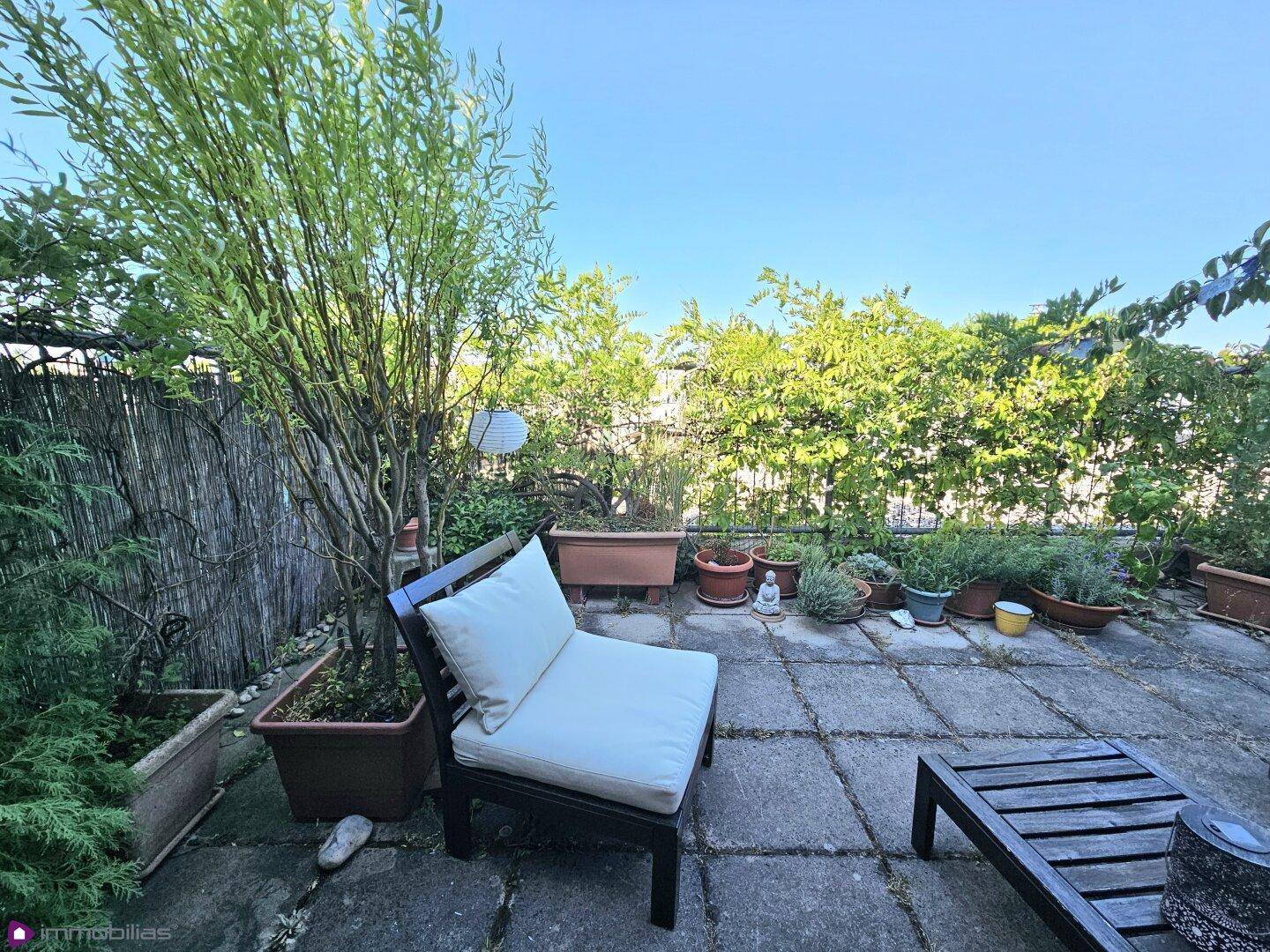 Entspannungsbereich auf der Terrasse mit üppiger Bepflanzung und Loungemöbeln.