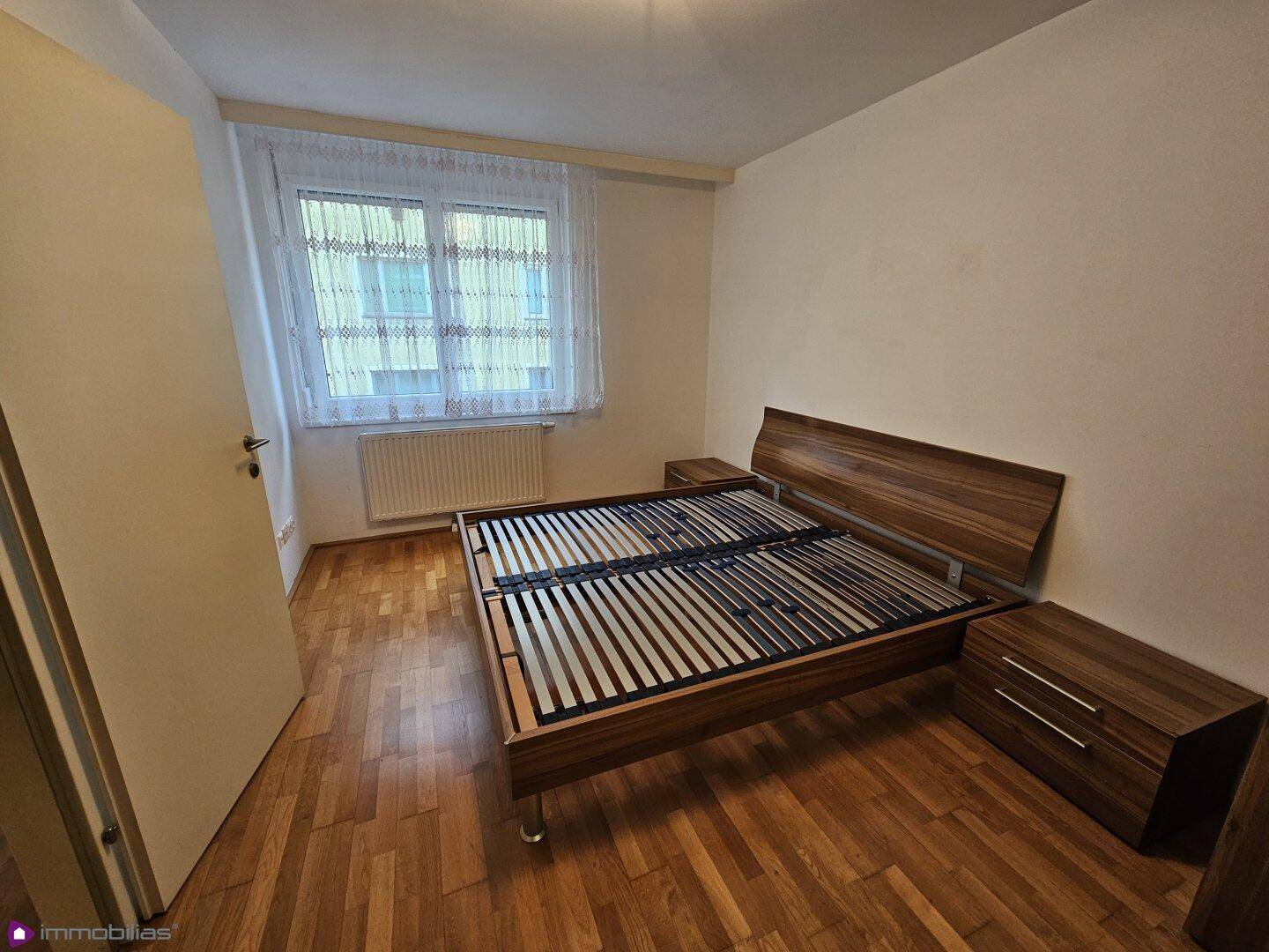 Schlafzimmer mit Holzboden, einem Doppelbettrahmen und passenden Nachttischen.