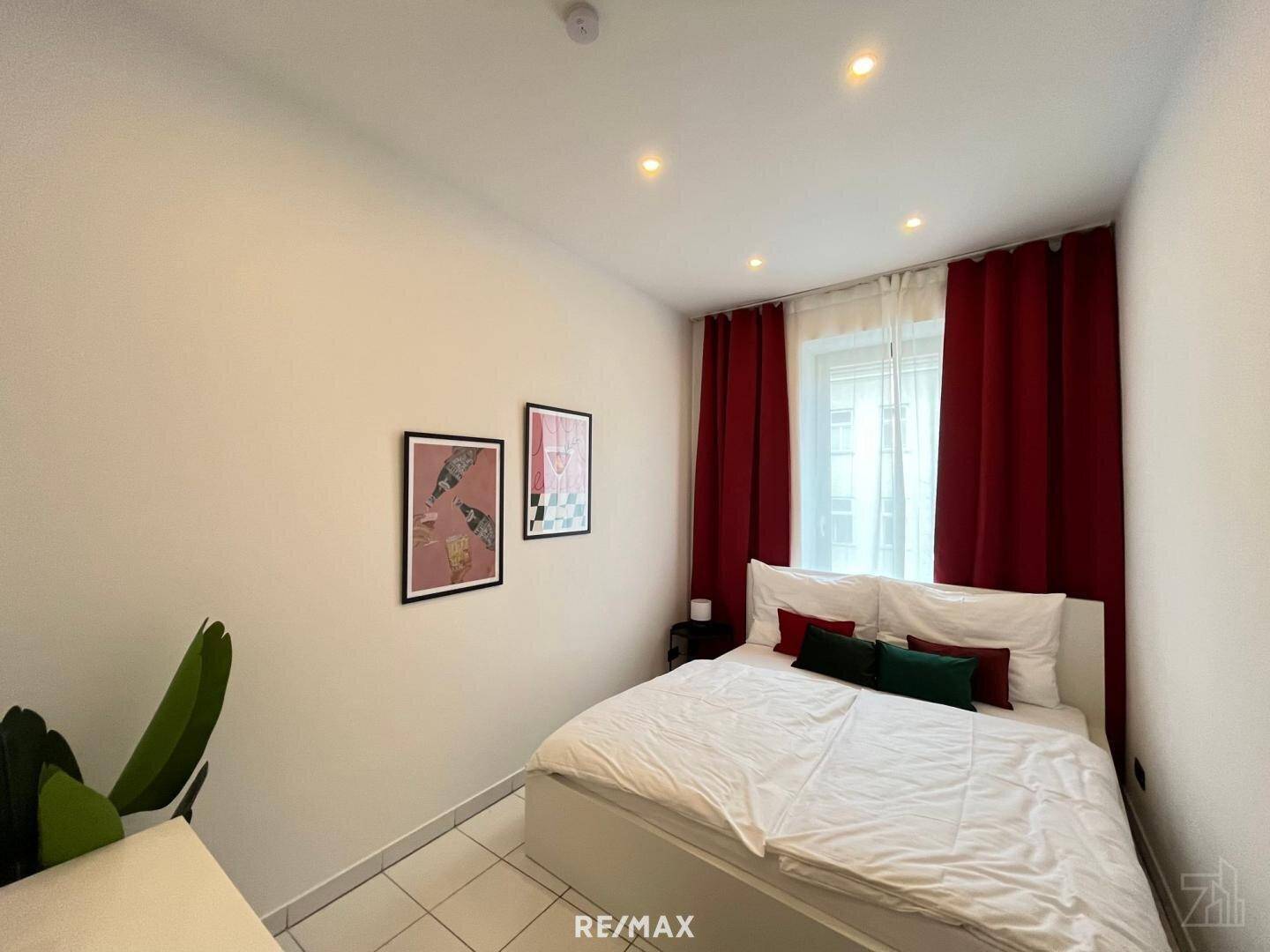 Gemütliches Schlafzimmer mit Doppelbett, roten Vorhängen und minimalistischer Dekoration.