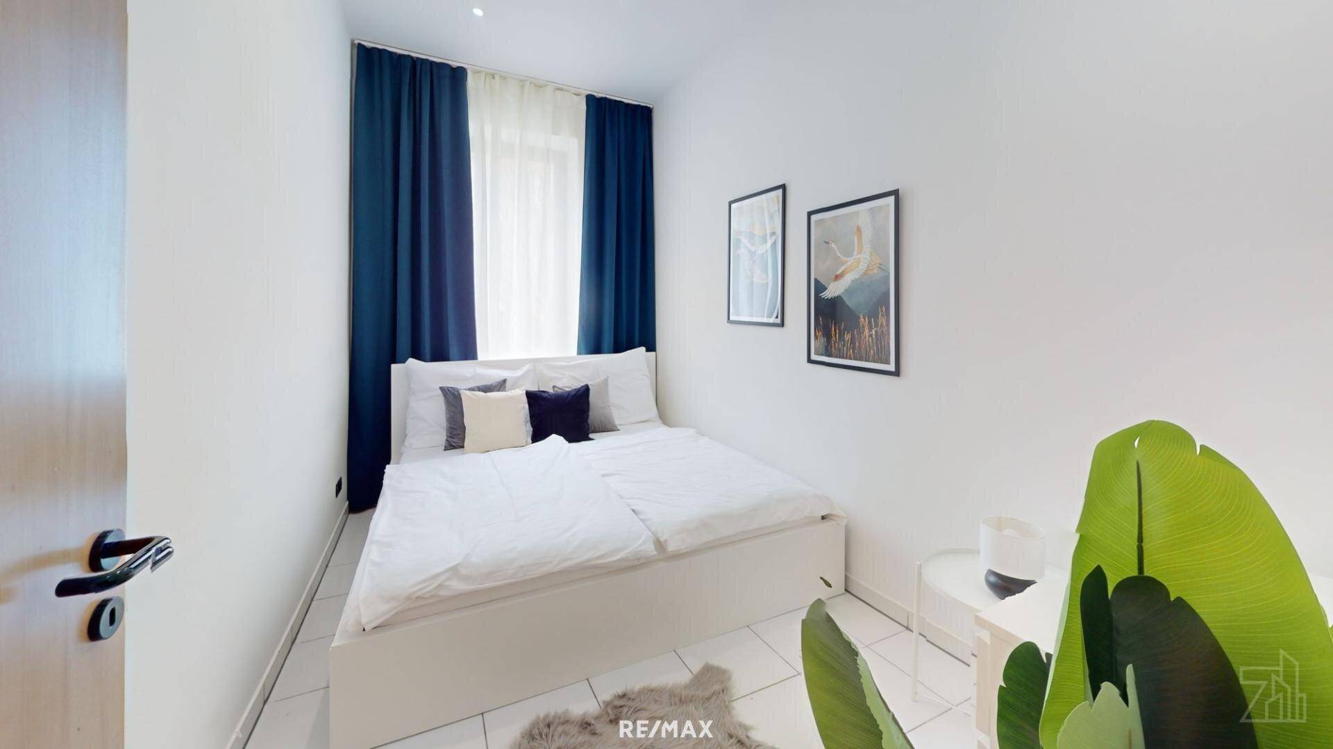 Helles Schlafzimmer mit Doppelbett, blauen Vorhängen und schlichtem, modernem Design.