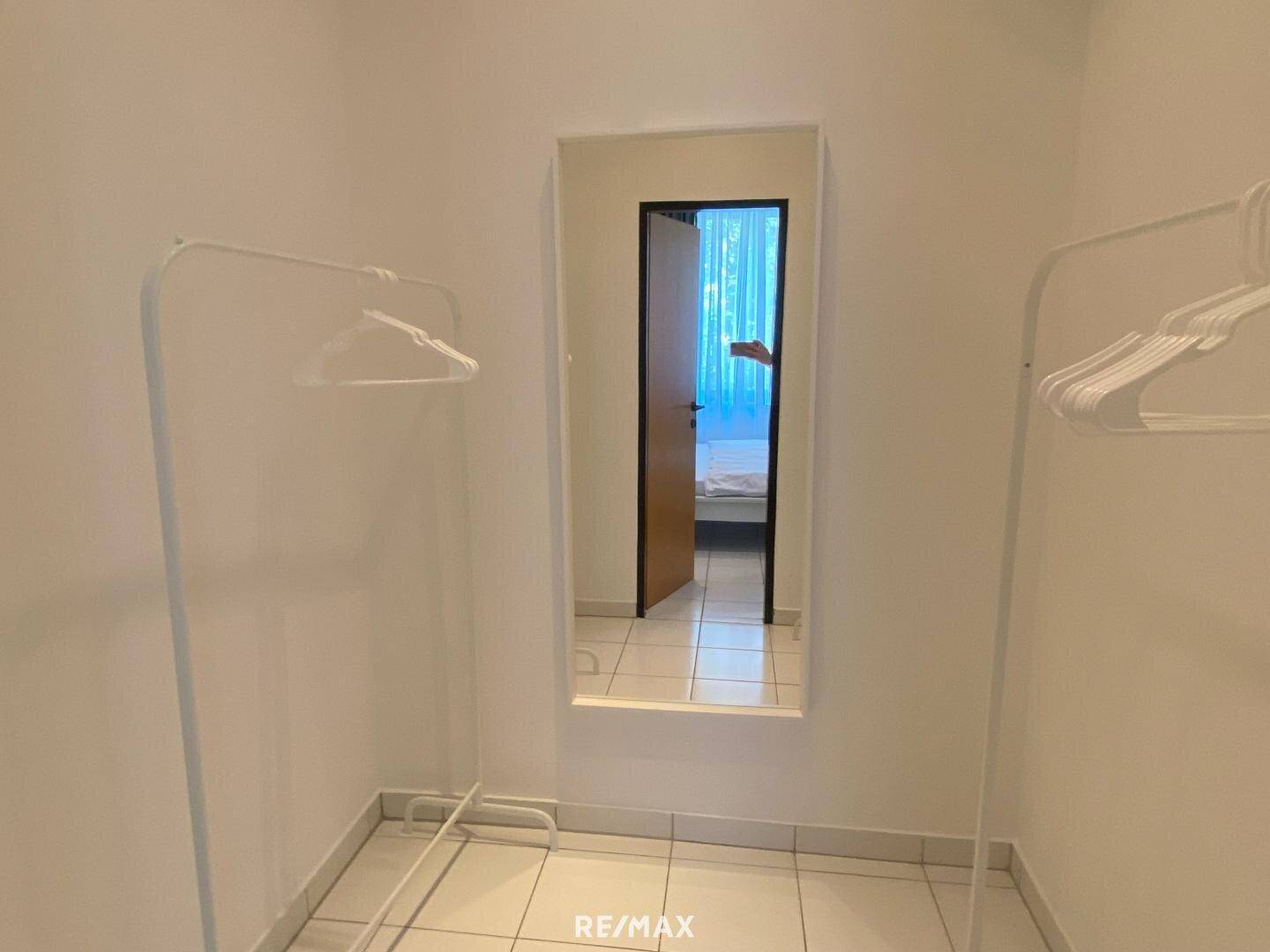 Kleiner Raum mit Kleiderständern und einem Wandspiegel, ideal als Ankleidebereich.