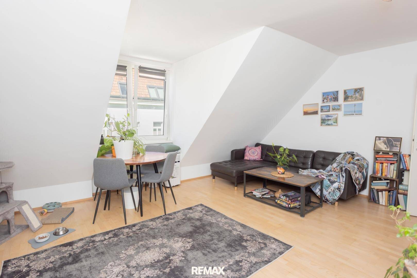 Heller Wohn- und Essbereich mit Holzboden, bequemer Couch und Dachschrägen.