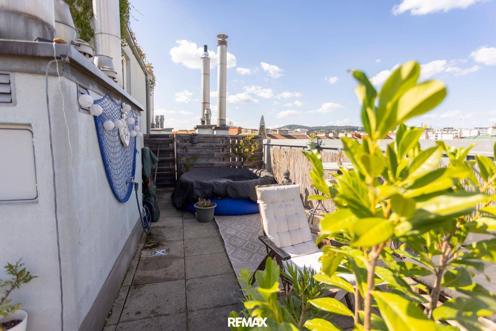 Entspannungsbereich auf der Dachterrasse mit Whirlpool und Liegestuhl unter blauem Himmel.