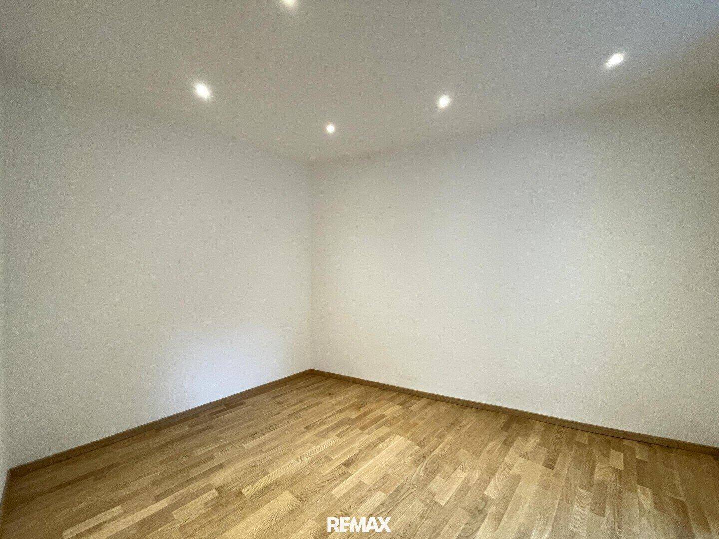 Helles Schlafzimmer mit Parkettboden und Deckenstrahlern, ideal für ruhige Nächte.