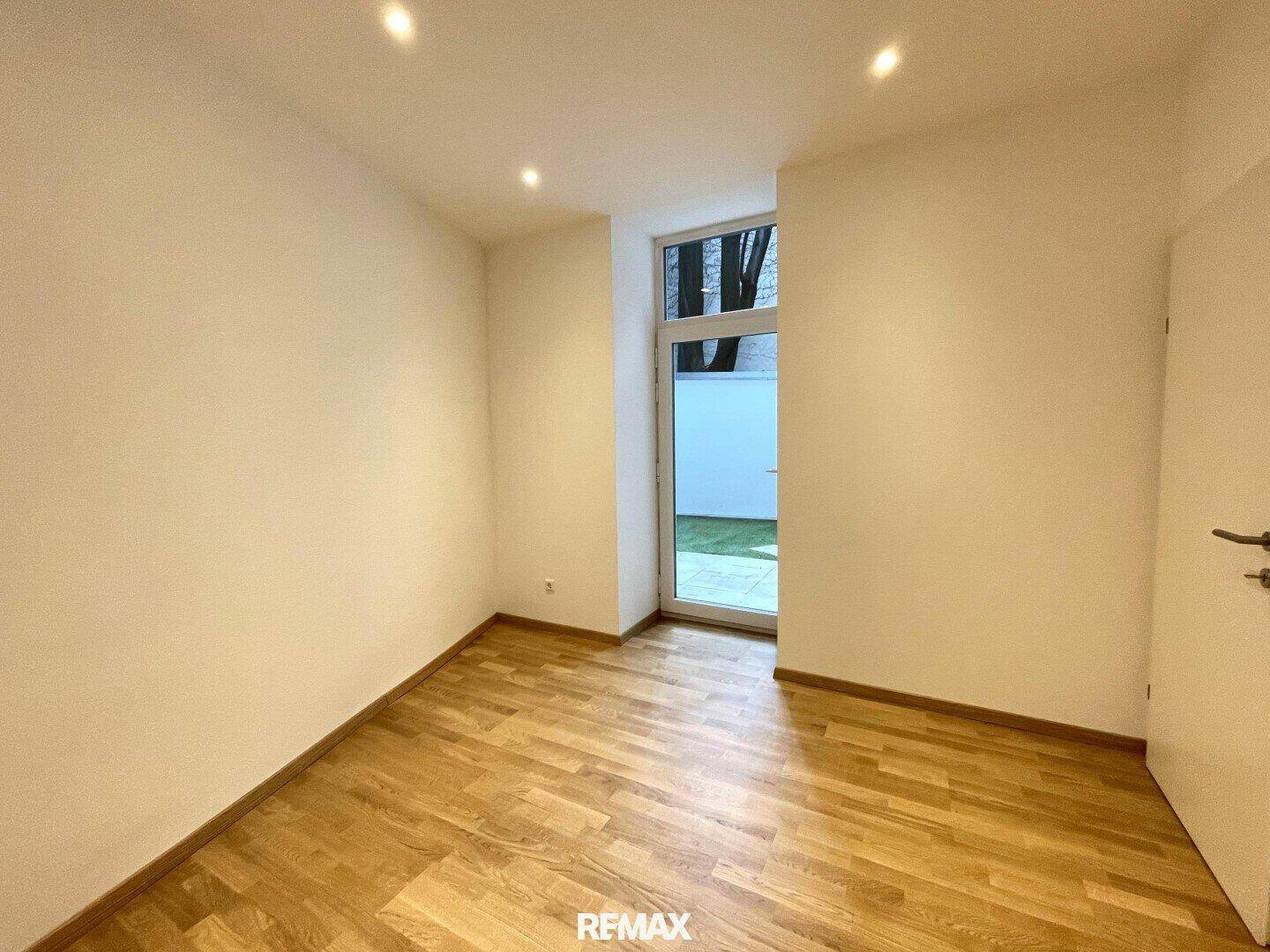 Schlafzimmer mit Parkettboden und direktem Zugang zum privaten Gartenbereich.