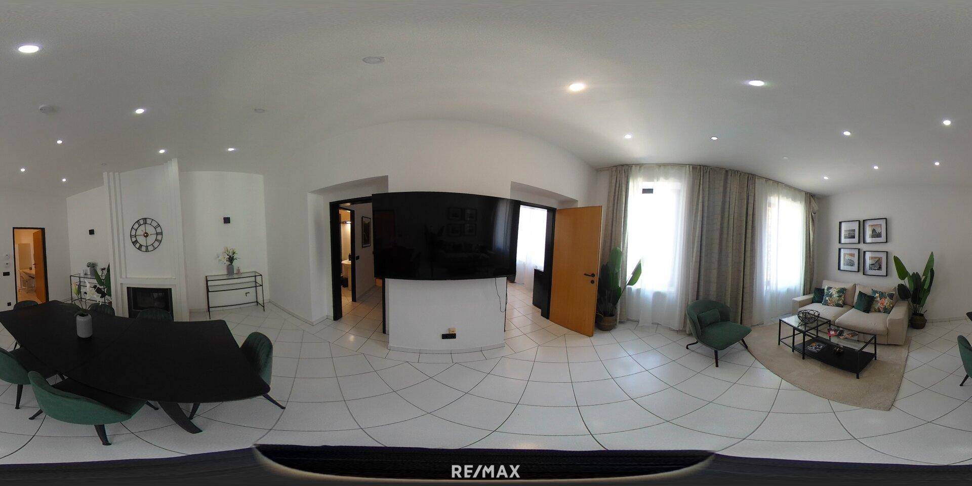 Panoramablick auf den offenen Wohn- und Essbereich mit Kamin und modernen Möbeln.