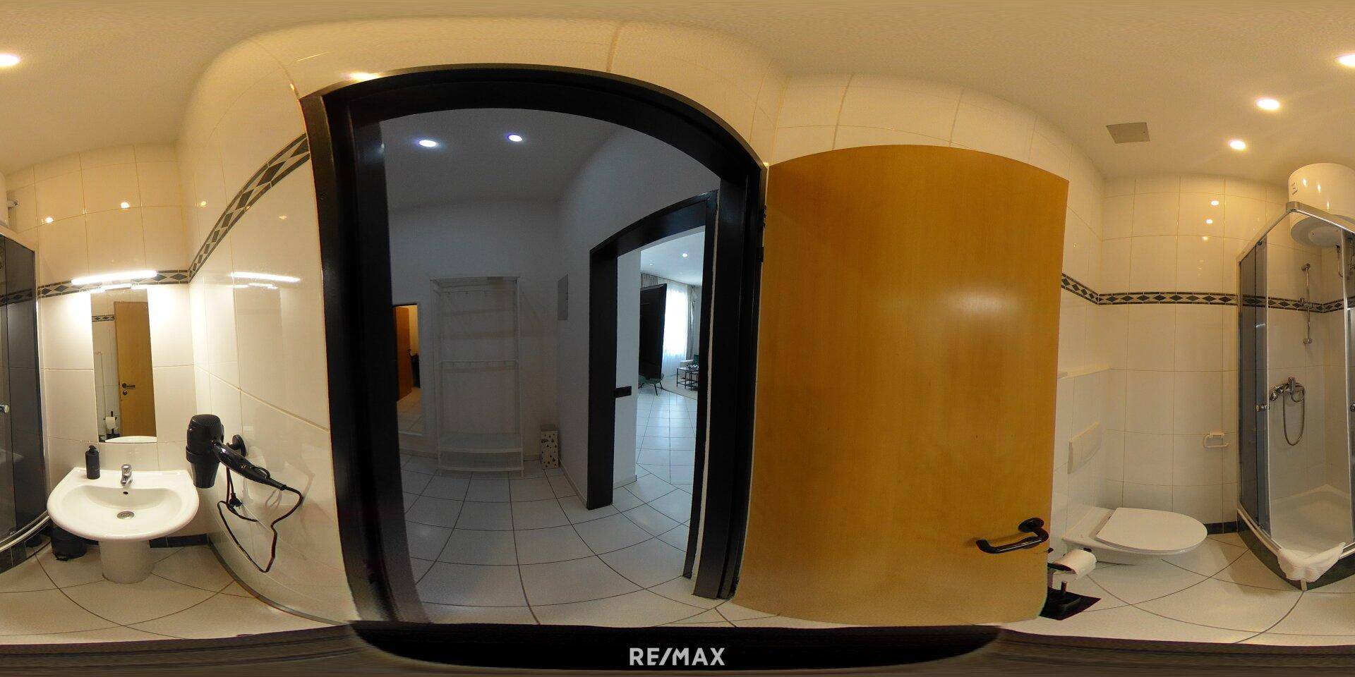 Panoramablick auf das Badezimmer mit Duschkabine, WC und Waschbecken.