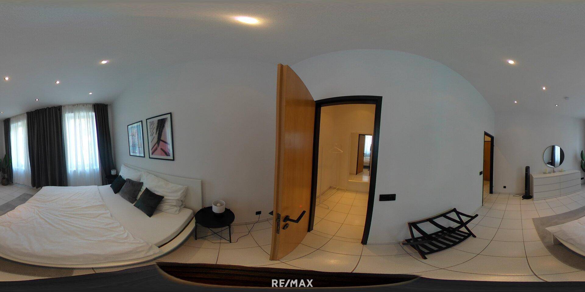 Panoramablick auf ein Schlafzimmer mit Doppelbett und Zugang zu einem weiteren Raum.