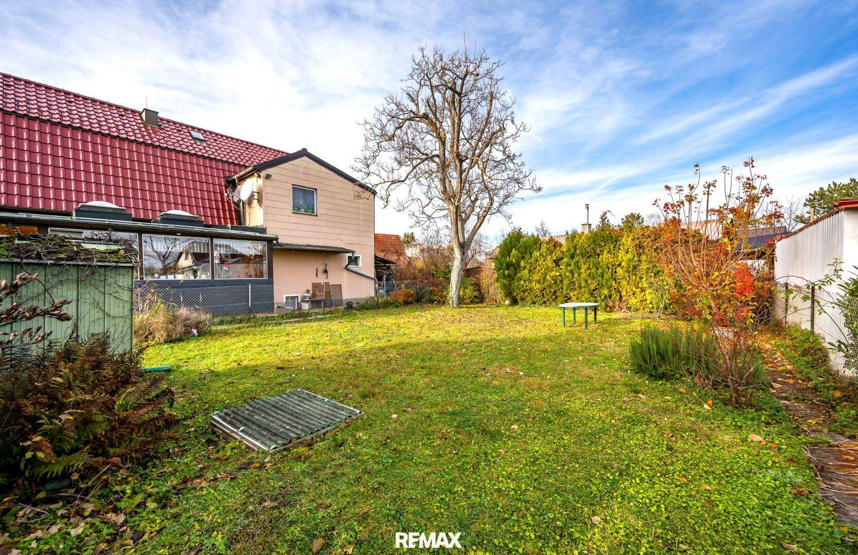 Hinterer Gartenbereich mit Rasenfläche, hohen Hecken und Blick auf das Wohnhaus.