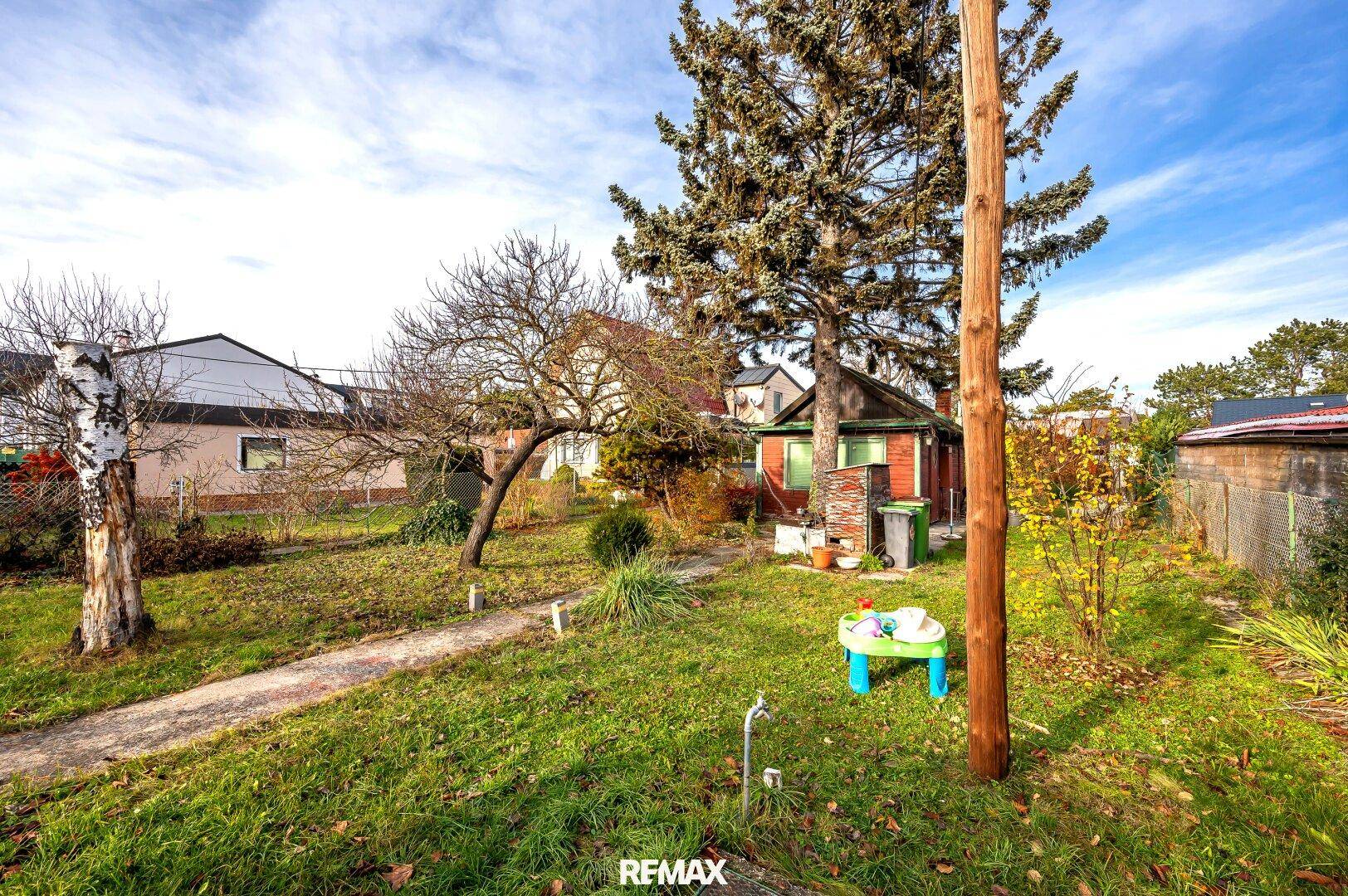 Weitläufiger Garten mit Rasenfläche, Bäumen und einem kleinen Spieltisch im Freien.