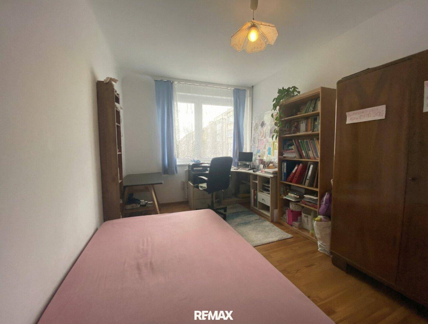 Helles Schlafzimmer mit Einzelbett, Schreibtisch und Bücherregalen, ideal als Kinder- oder Arbeitszimmer.