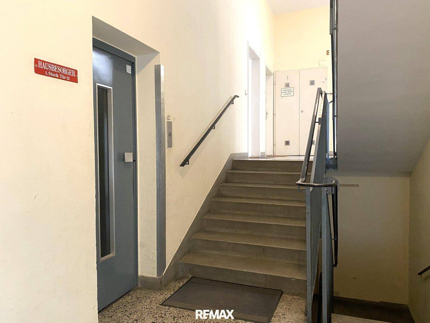 Treppenhaus mit Betontreppen, Handlauf und Zugang zum Aufzug, für bequemen Zugang zu den Etagen.