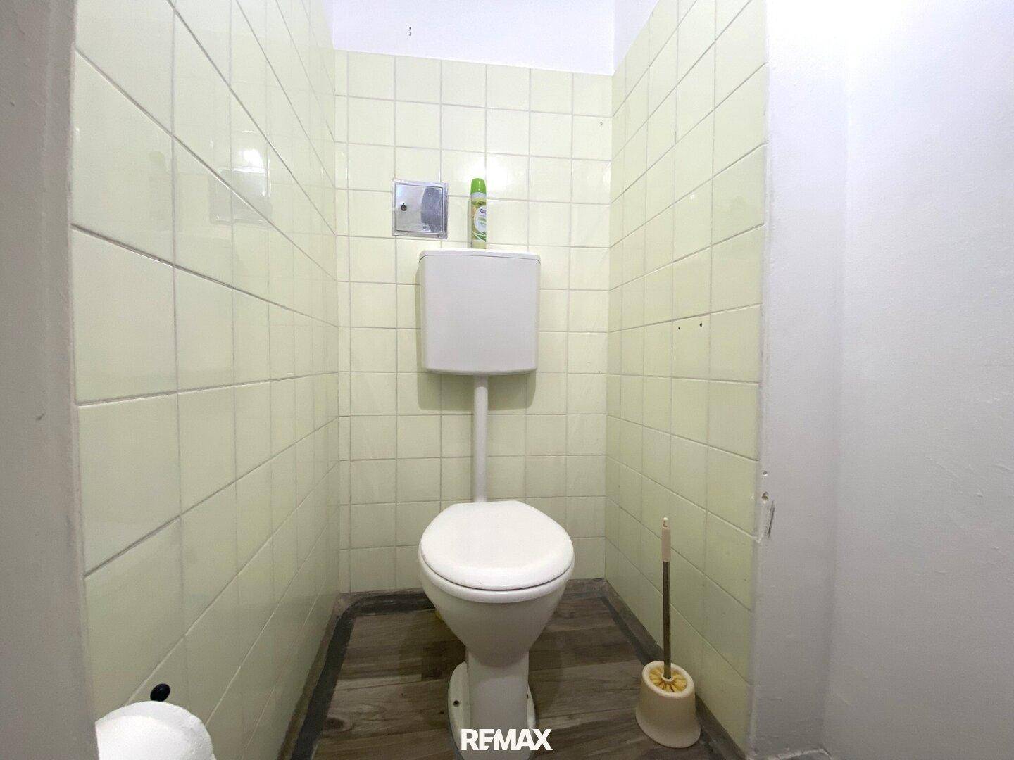 Separates WC mit Steh-Toilette und hellgrünen Wandfliesen, funktional und sauber.