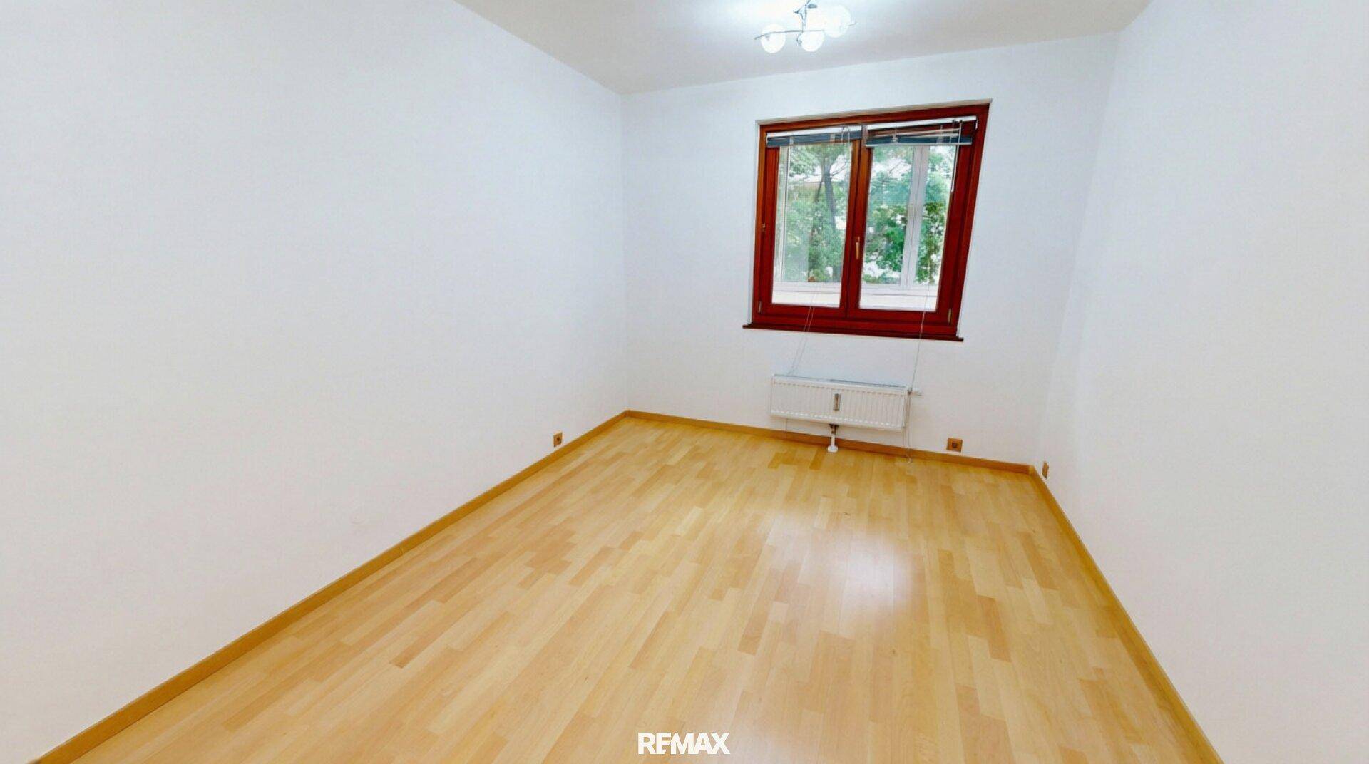 Ruhiges Schlafzimmer mit hellem Parkettboden und Fenster, ideal für erholsame Nächte.