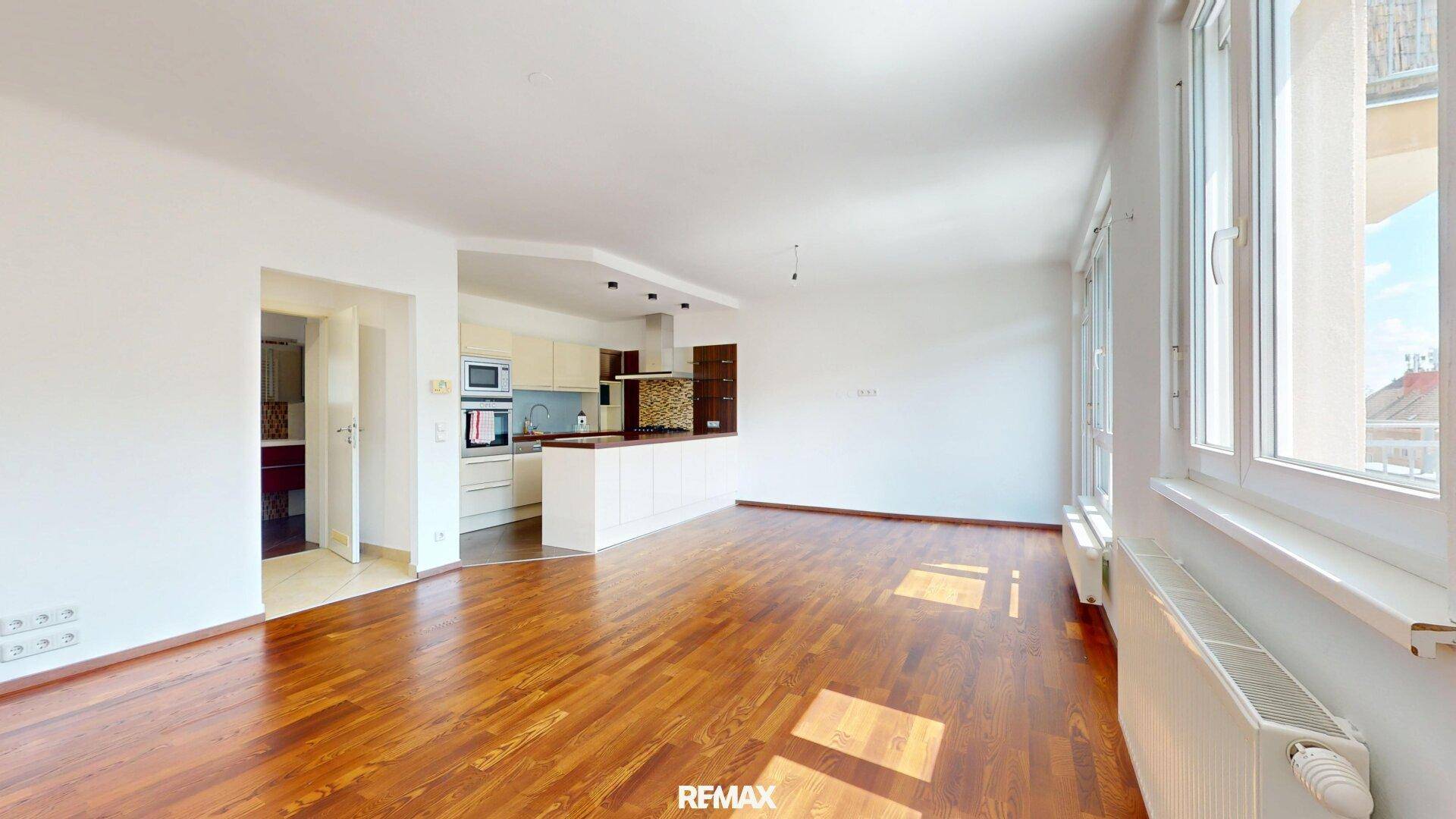 Offener Wohnbereich mit integrierter Küche und Holzboden, ideal für modernes Wohnen.