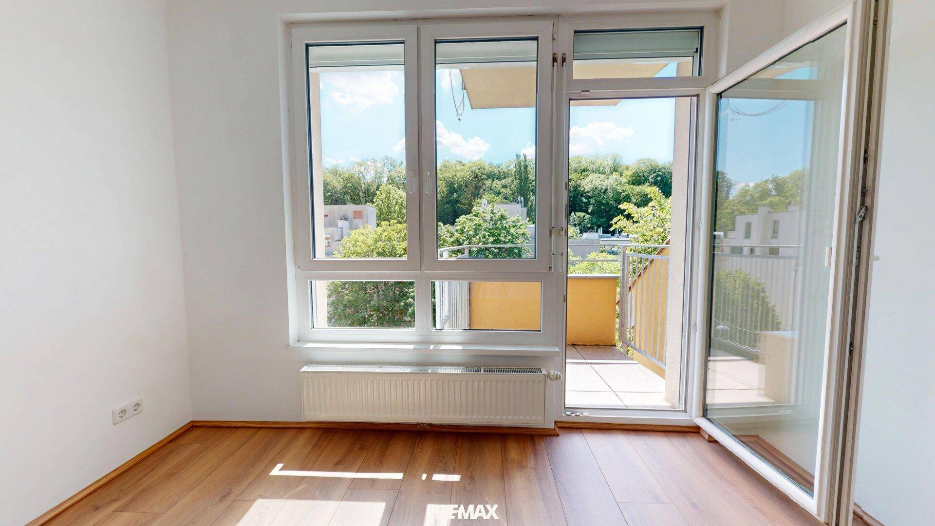 Lichtdurchfluteter Wohnraum mit Laminatboden und direktem Zugang zu einem sonnigen Balkon.