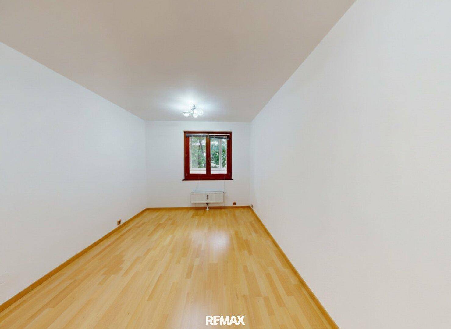 Helles, leeres Zimmer mit Parkettboden und einem Fenster, ideal als Schlafzimmer.