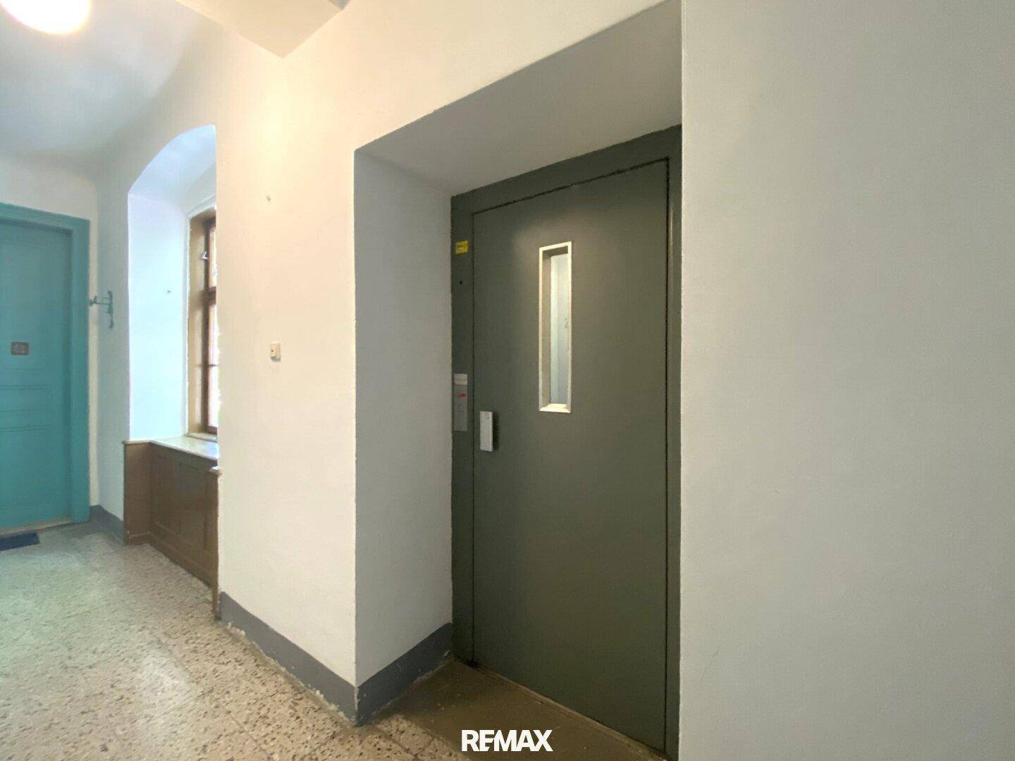 Heller Hausflur mit einem modernen Aufzug, der den Zugang zu den oberen Etagen des Altbaus ermöglicht.