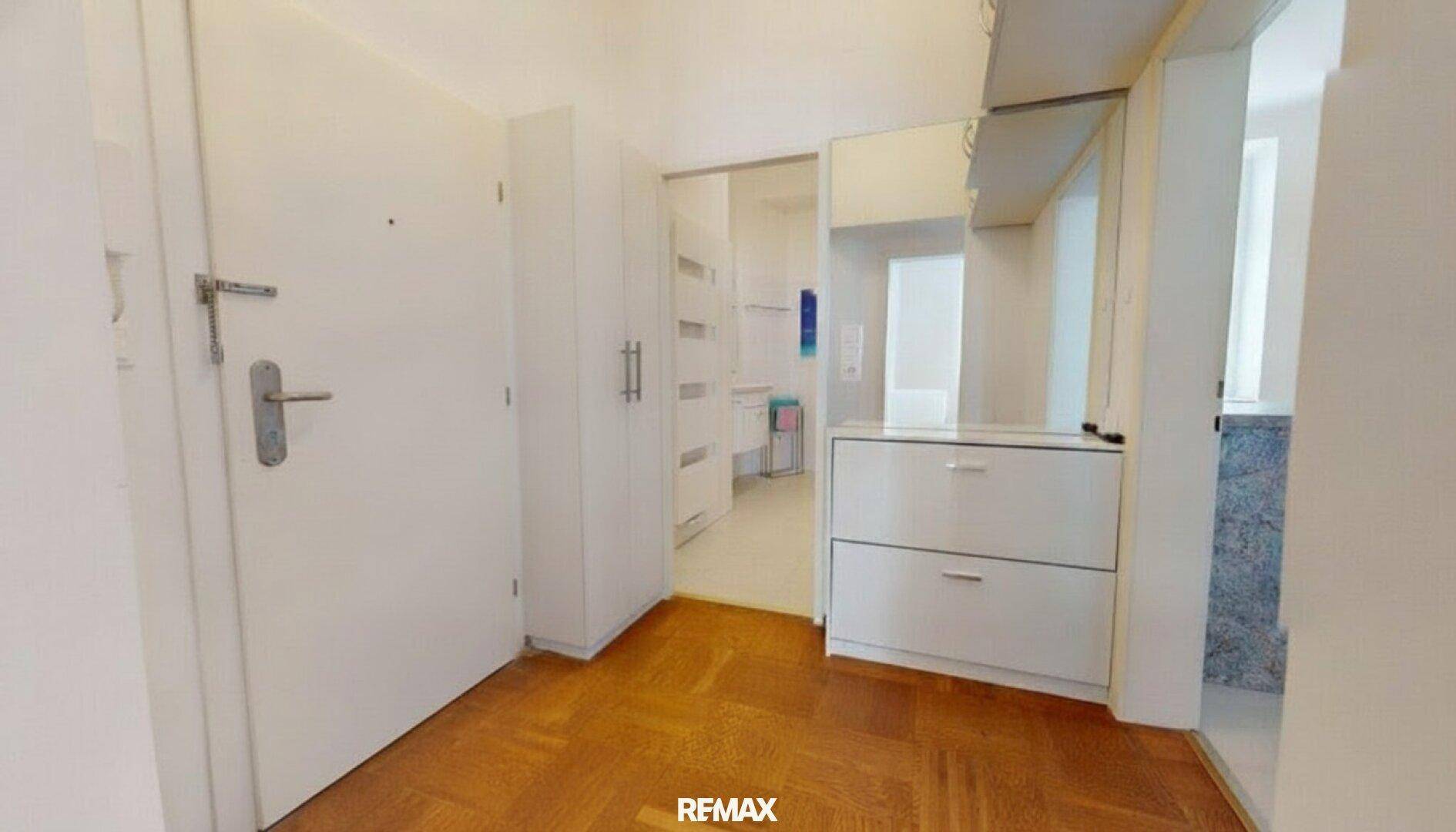 Heller Flur mit Parkettboden, Spiegelschrank und Zugang zum Badezimmer.