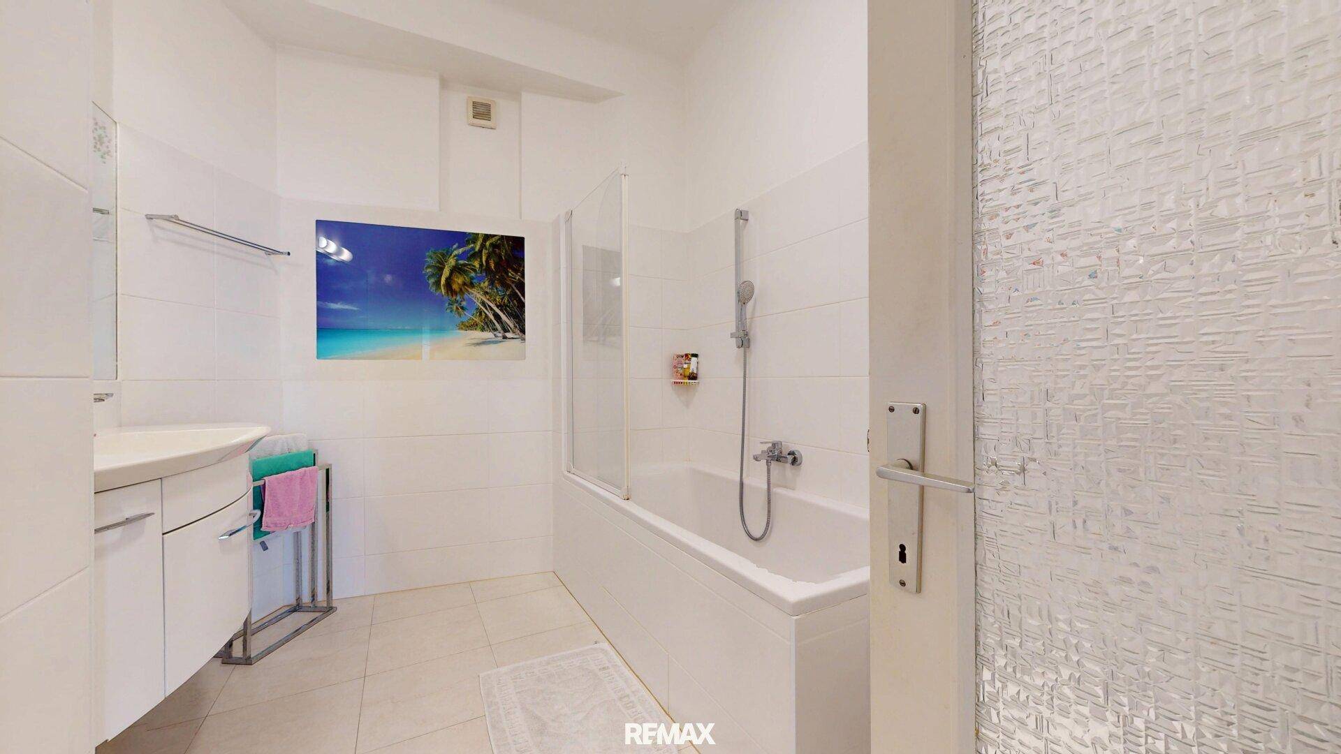 Modernes Badezimmer mit Badewanne, Duschbereich und Waschbecken in hellen Fliesen.
