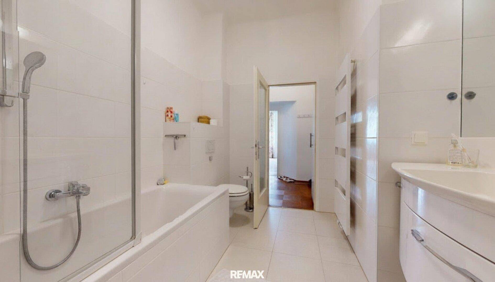 Modernes Badezimmer mit Badewanne, Duschabtrennung, WC und weiß gefliesten Wänden.