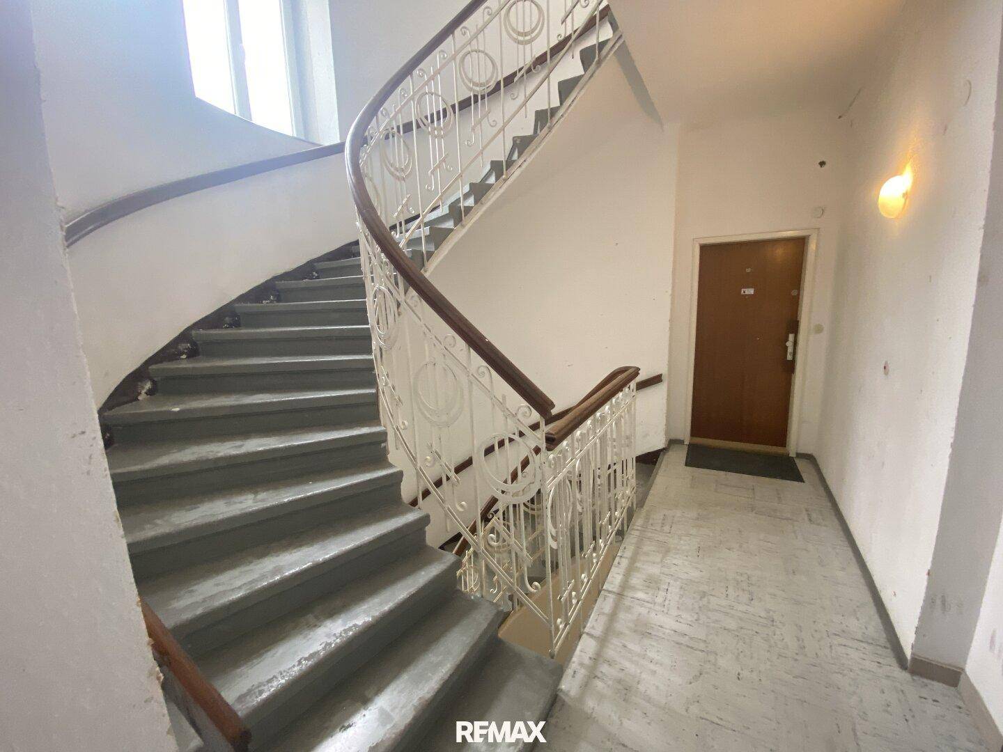 Historisches Treppenhaus mit geschwungenem Geländer und natürlichem Lichteinfall.