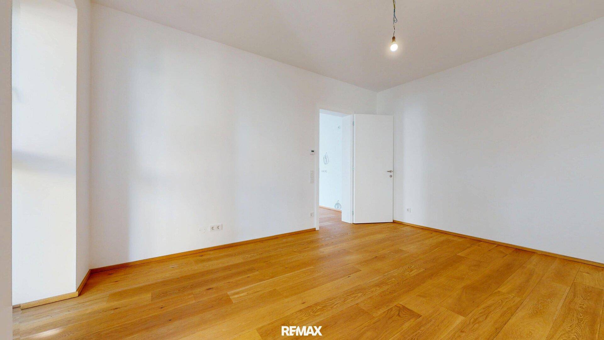 Leeres Schlafzimmer mit Holzboden und weiß gestrichenen Wänden, bereit zur Einrichtung.