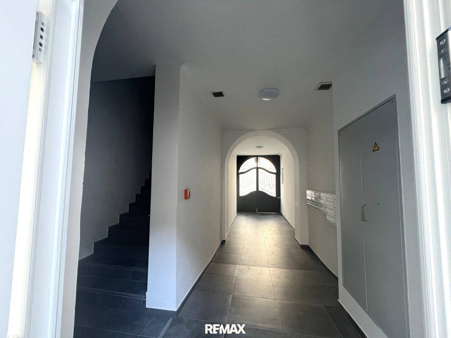 Eingangsbereich mit dunklem Fliesenboden, gewölbter Decke und Zugang zum Treppenhaus.