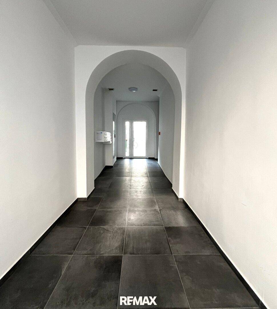 Langer, gefliester Flur mit eleganten Bögen und hellem Eingangsbereich.