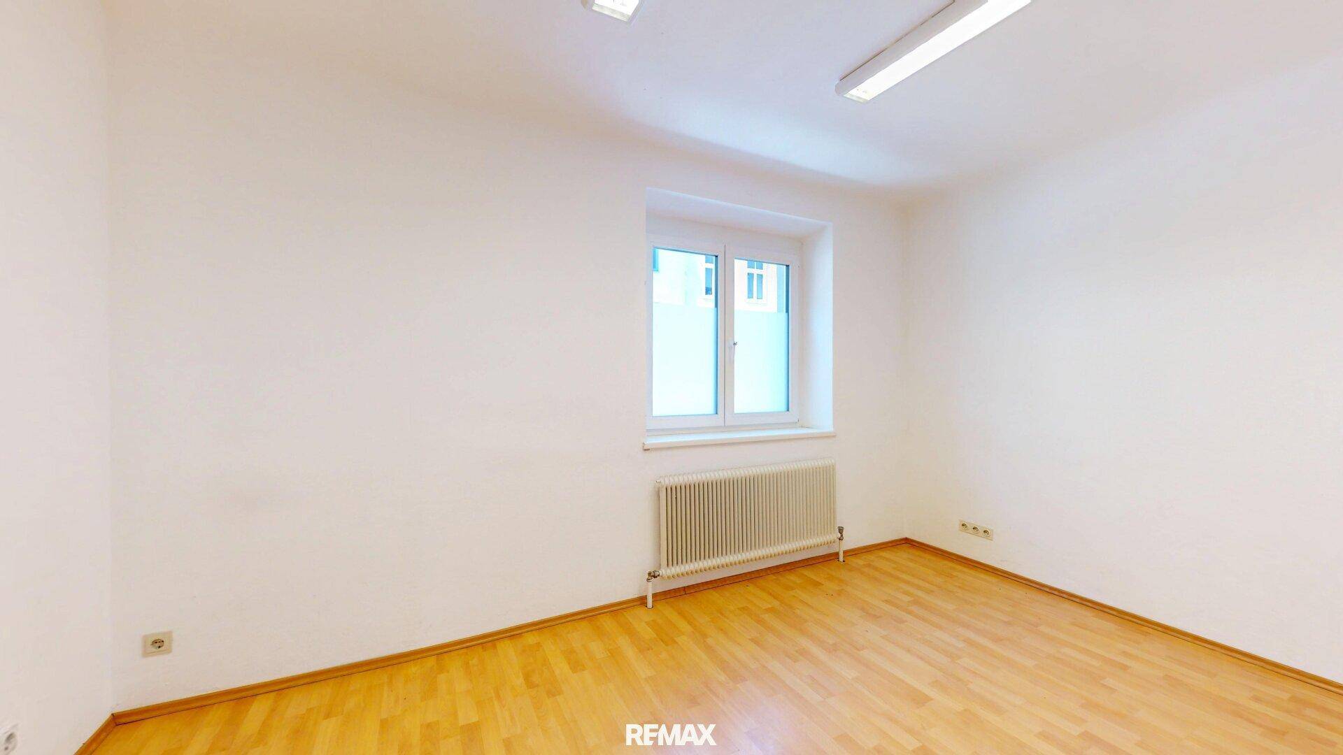 Einfacher Raum mit Holzfußboden und Fenster, ideal für ein kleines Büro oder Gästezimmer.