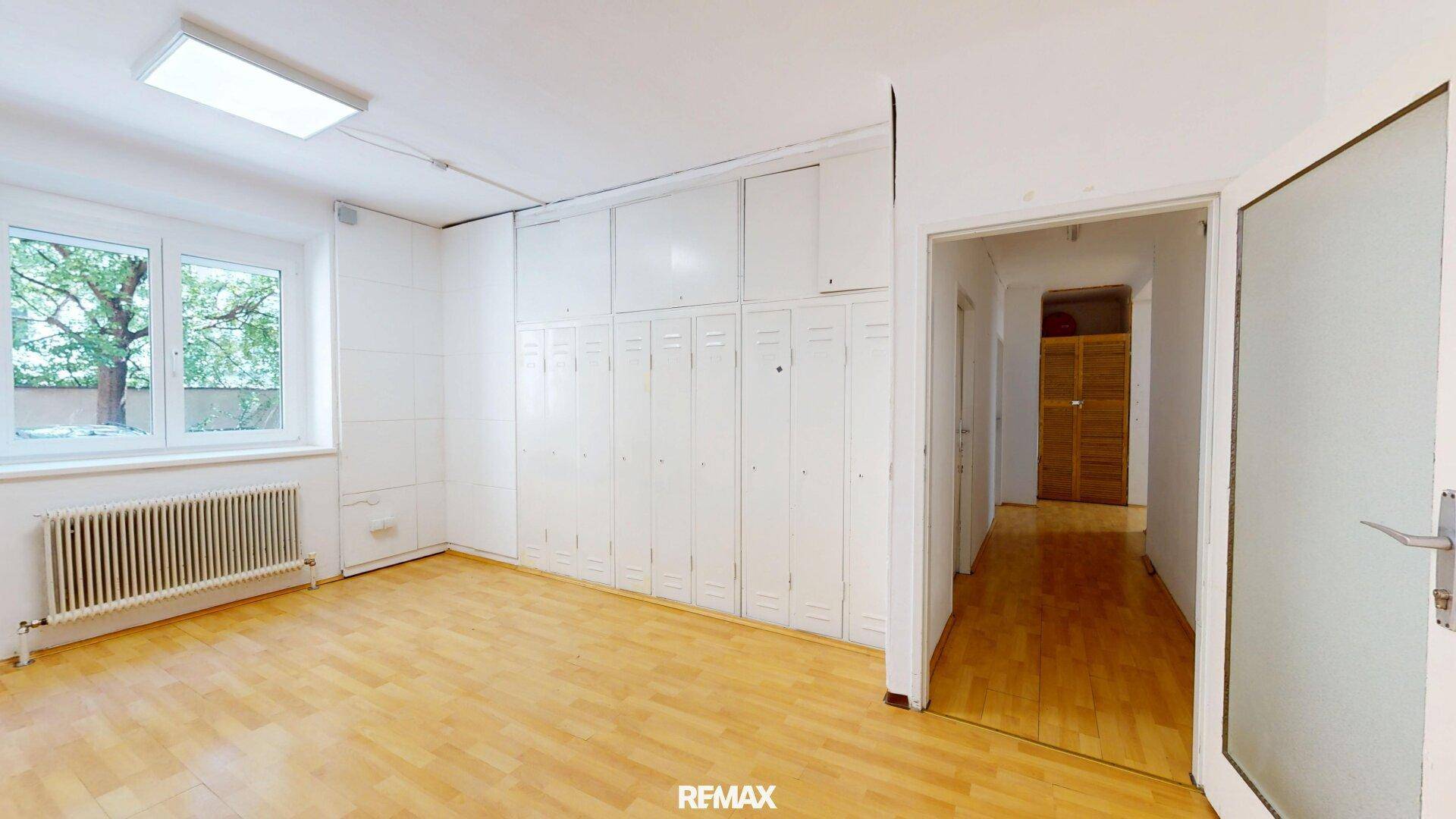 Großer Raum mit Holzfußboden und Einbauschränken, ideal für Lagerung oder Büro.