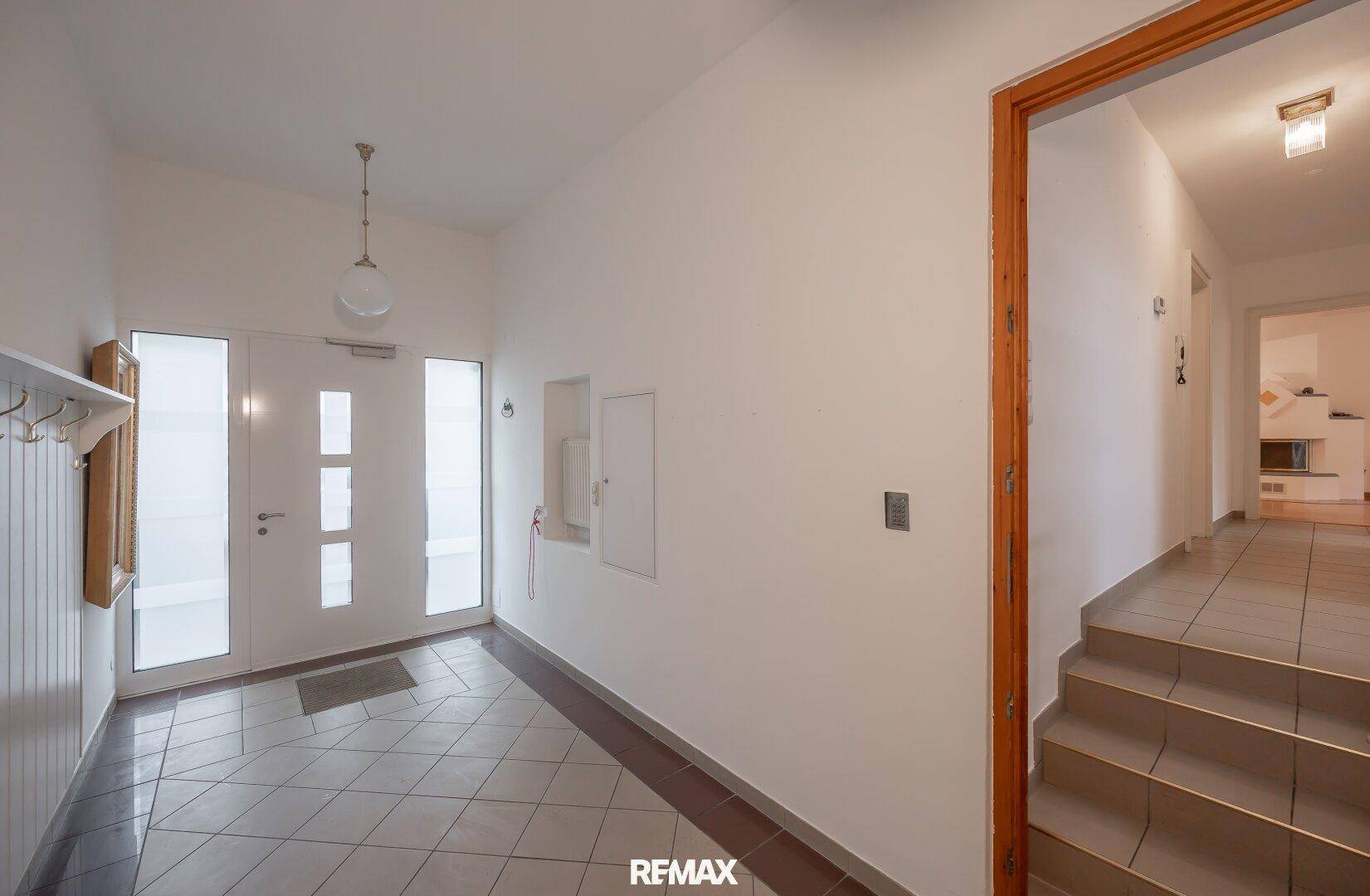 Heller Eingangsbereich mit Fliesenboden, Garderobe und Zugang zu weiteren Räumen.