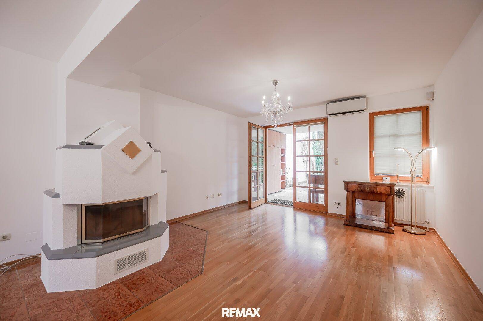 Geräumiges Wohnzimmer mit Parkettboden, Kamin und Zugang zur Terrasse.