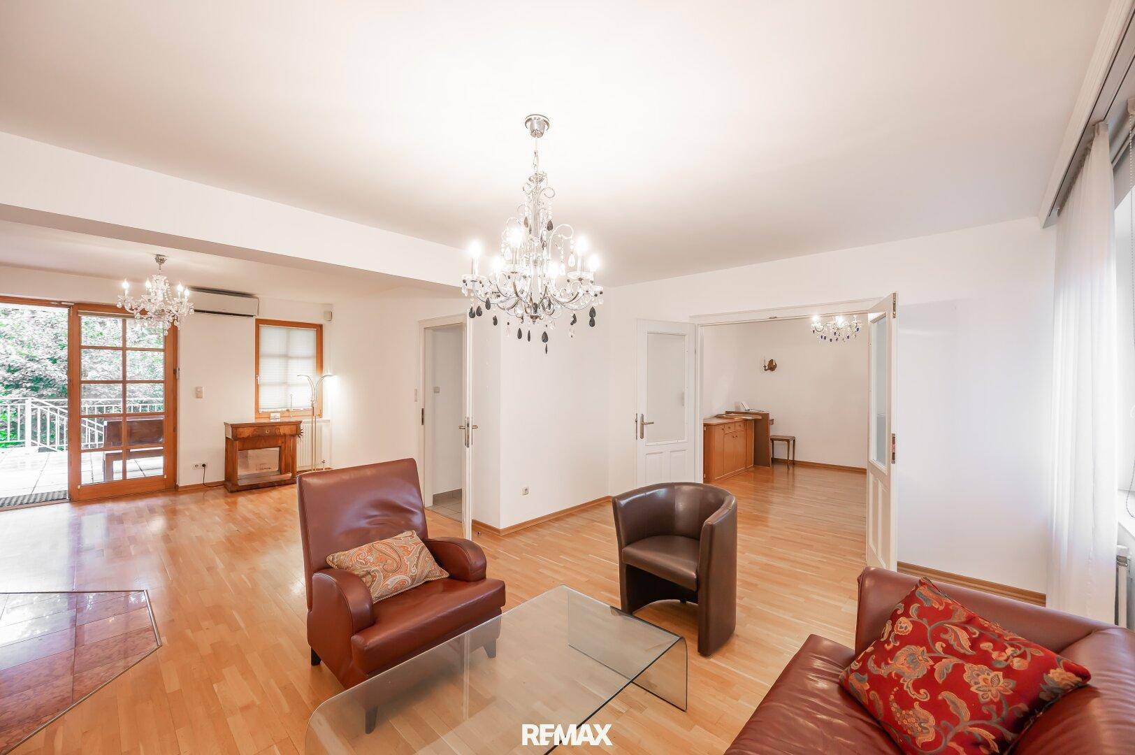 Elegantes Wohnzimmer mit Parkettboden, Kronleuchter und bequemen Ledersesseln.