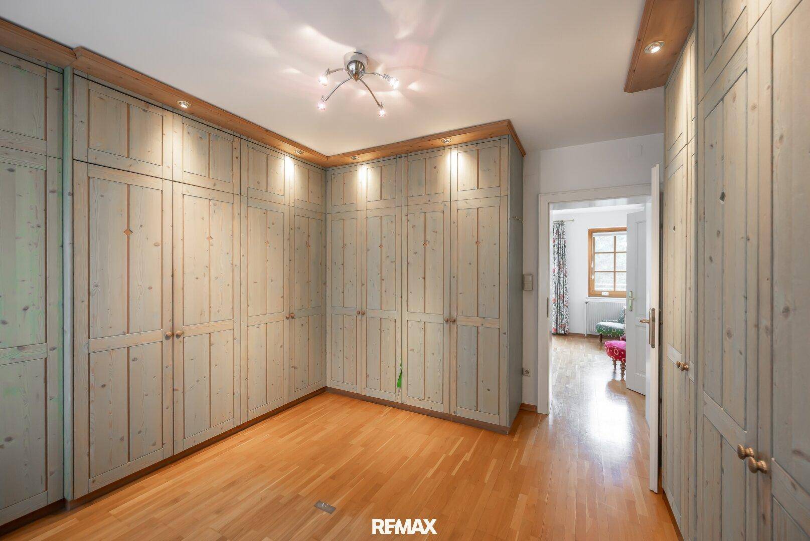 Geräumiges Zimmer mit Holzboden und maßgefertigten Holzschränken für viel Stauraum.