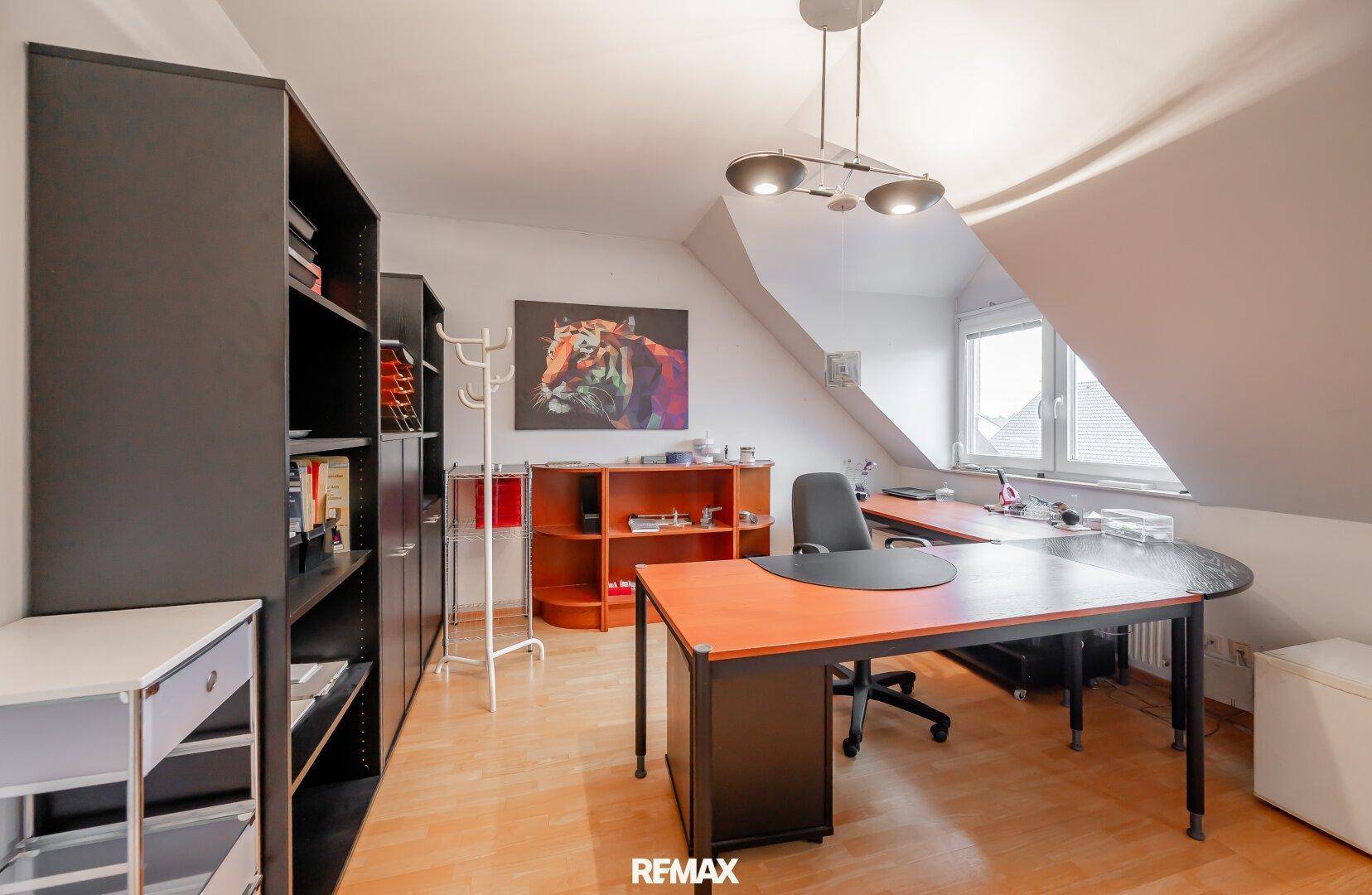 Helles Dachgeschoss-Büro mit Schreibtisch, Regalen und Dachfenster.