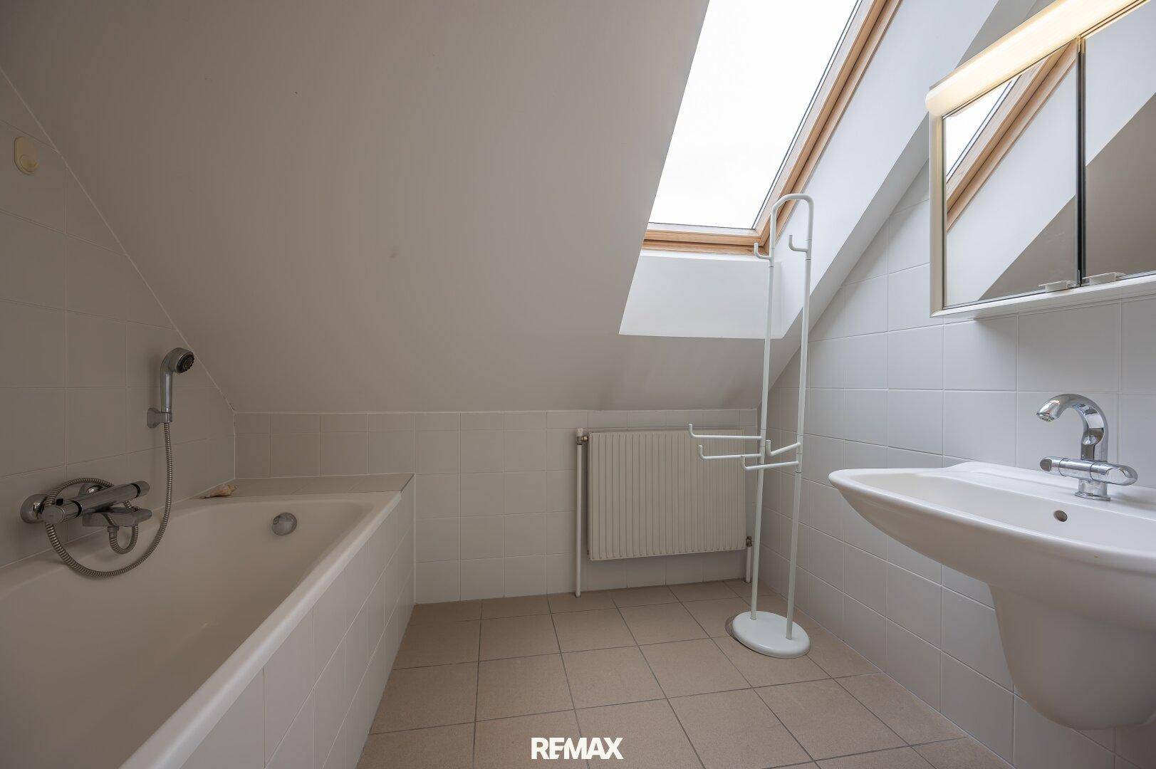 Badezimmer im Dachgeschoss mit Badewanne, Waschbecken und Dachfenster.