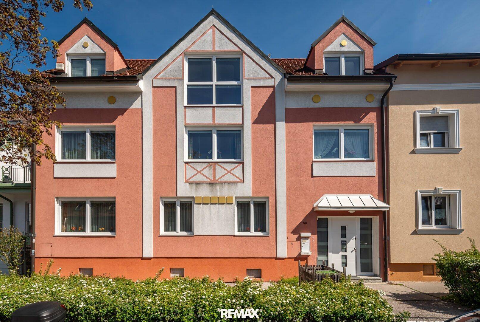Attraktive Fassade eines Mehrfamilienhauses in Pastellfarben mit vielen Fenstern.