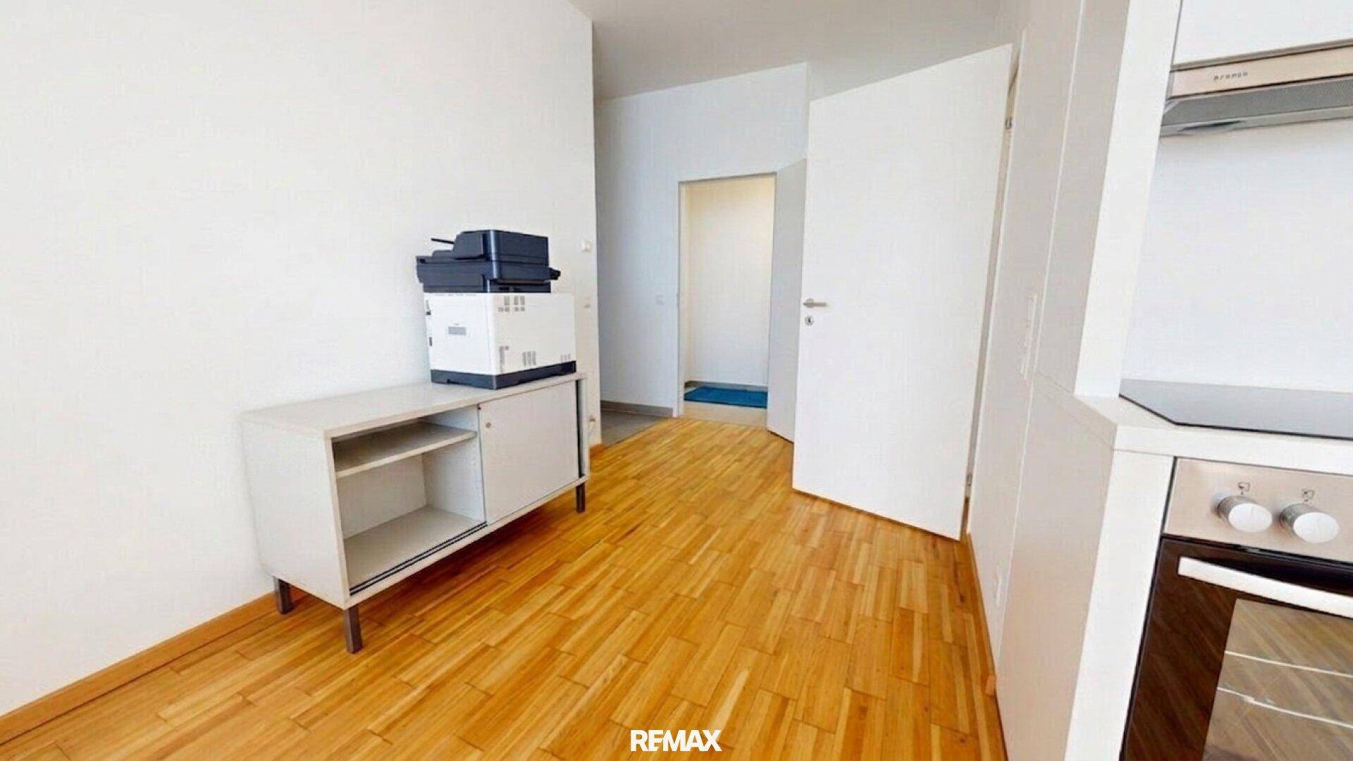 Flurbereich mit Holzboden und einem Sideboard, der zu einem weiteren Raum führt.