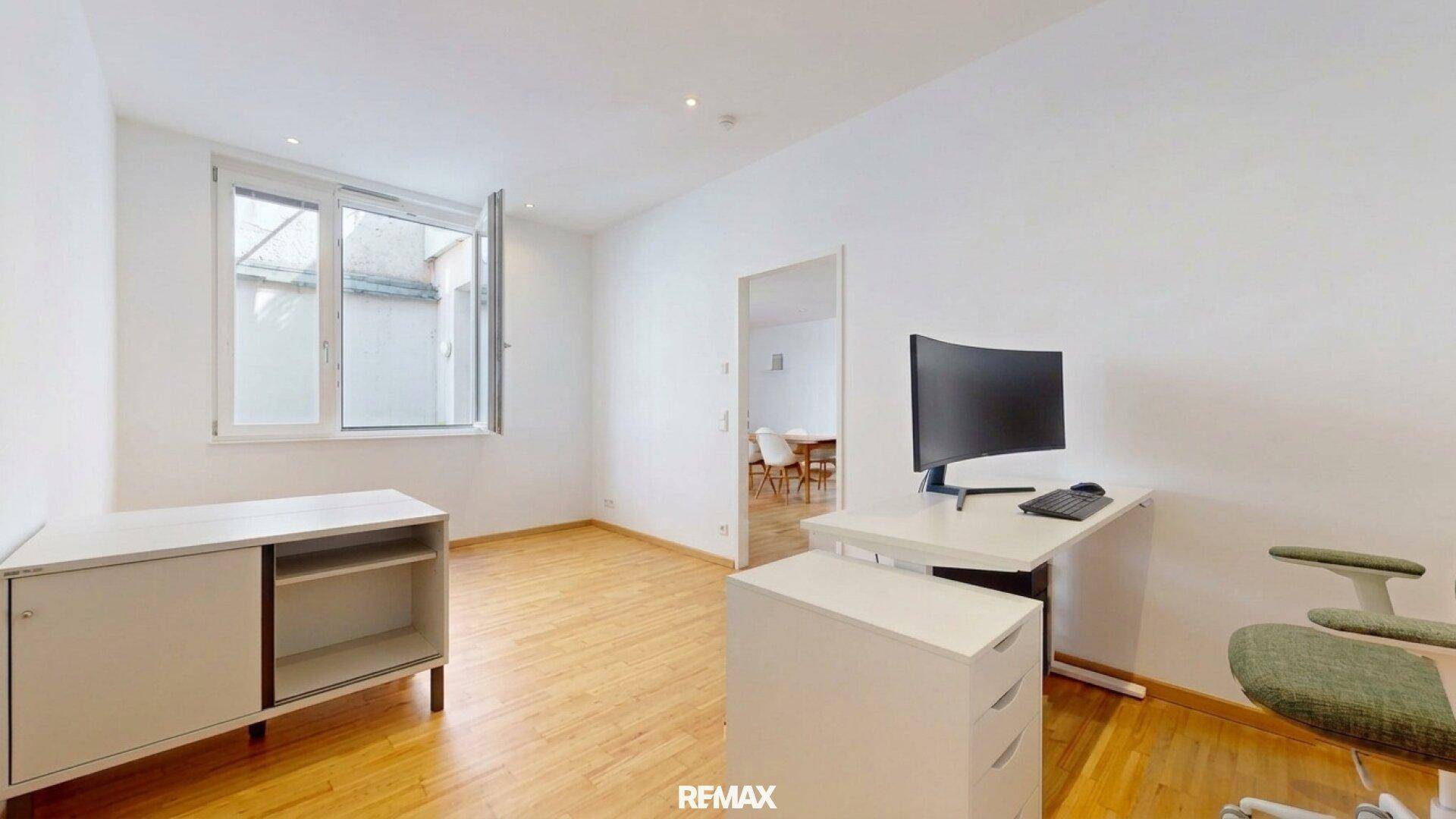 Helles Büro mit Schreibtisch, Bürostuhl und Fenster zum Innenhof.
